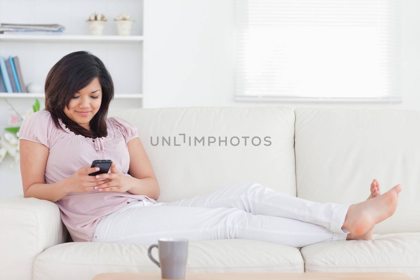 Woman smiling while looking at a phone in a living room