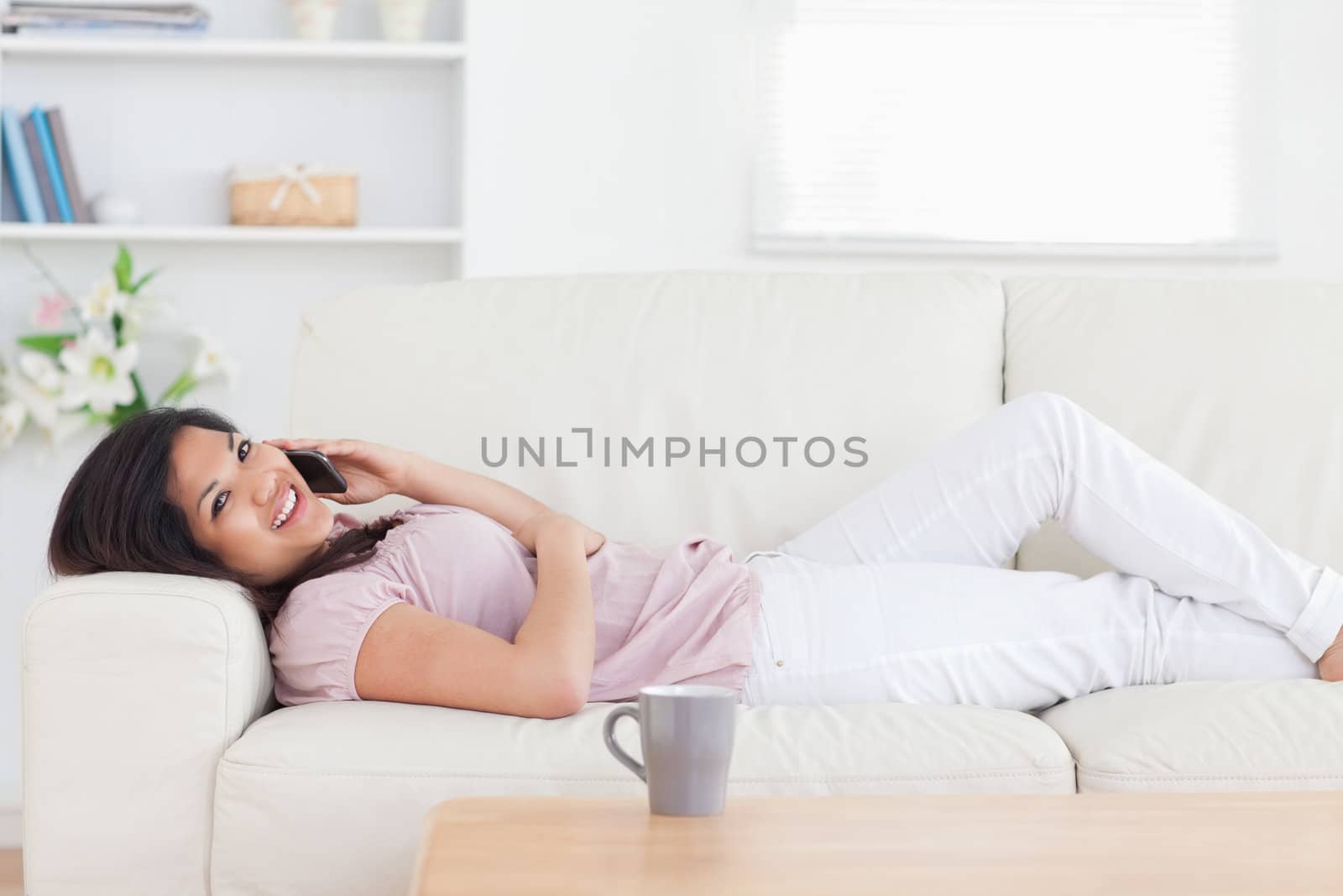 Woman resting in a sofa while holding a phone in a living room