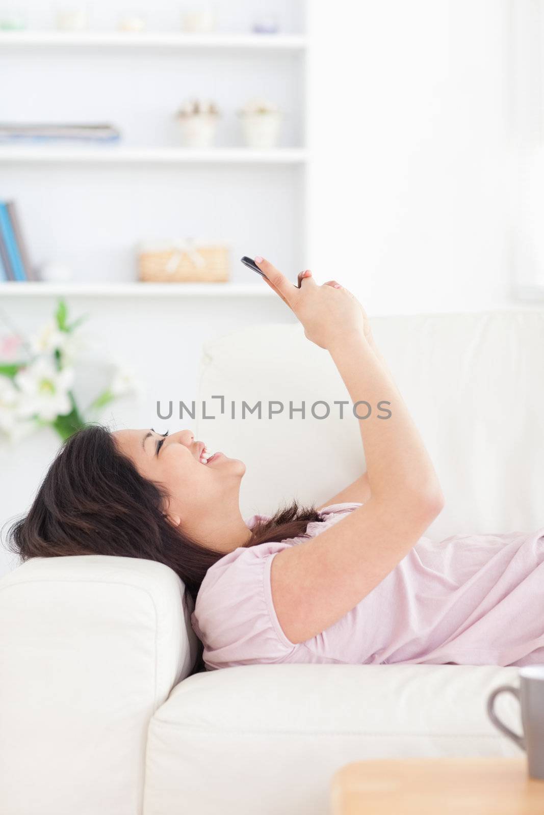 Woman laughing while resting on a couch and looking at a phone in a living room