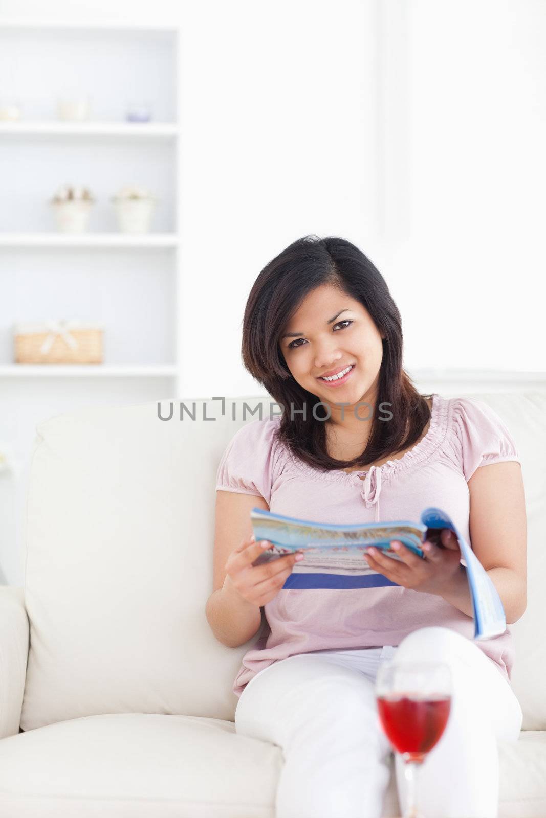 Woman holding a magazine and sitting on a couch in a living room