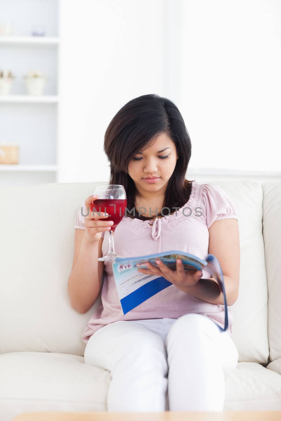 Woman sits on a couch and holds a magazine in a living room