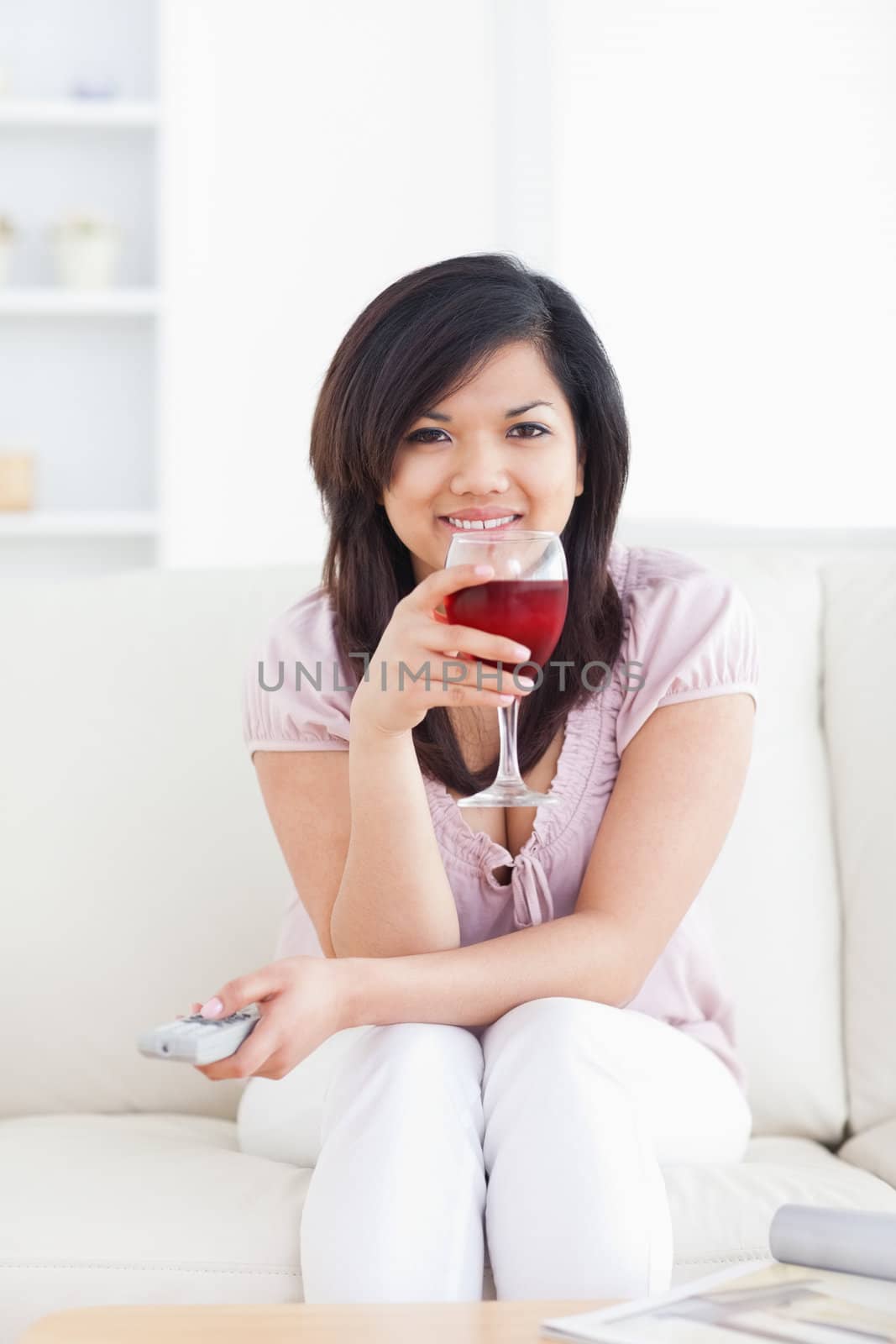 Woman smiling and holding a glass of red wine in a living room