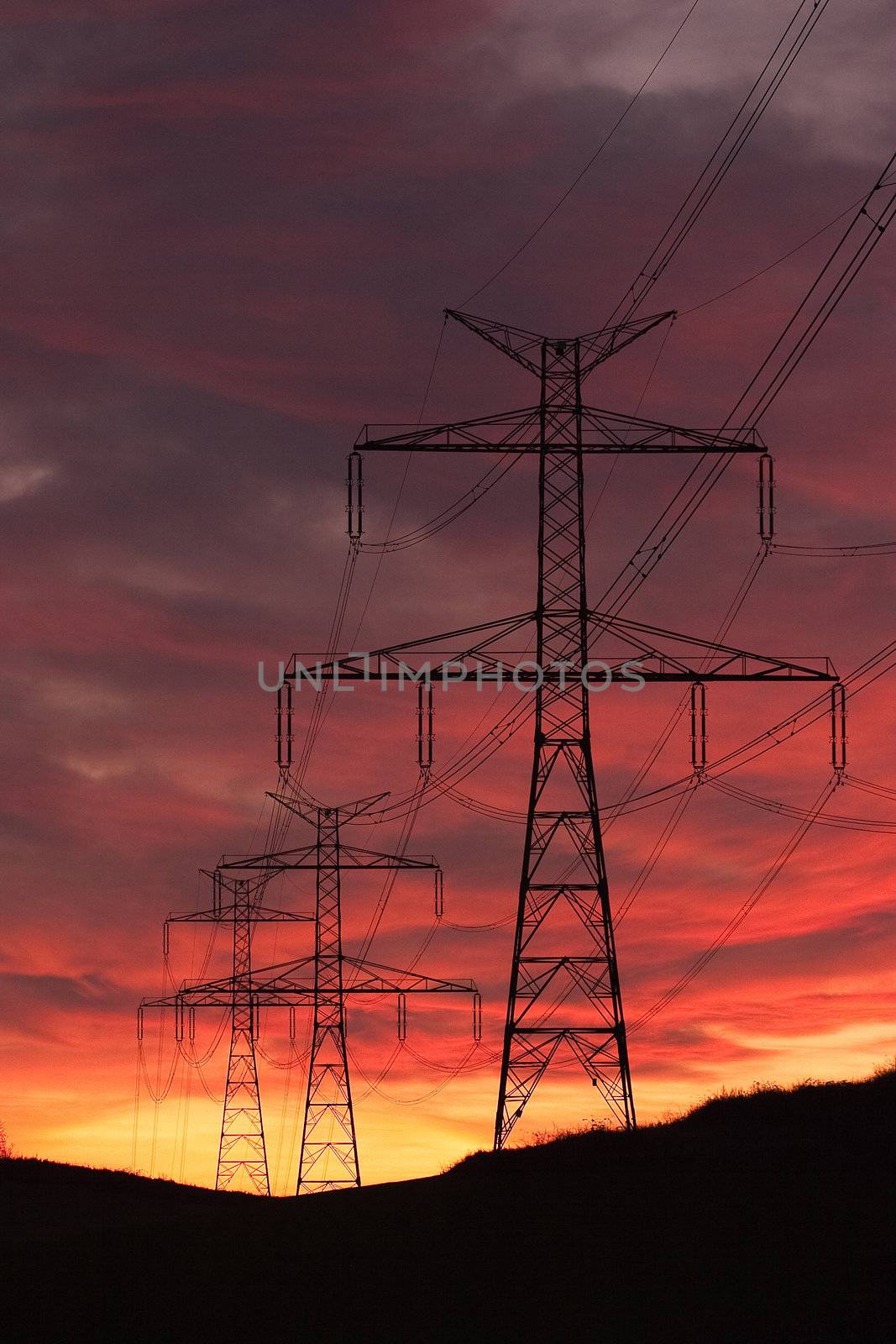 Transmission towers on the hills at red sunset