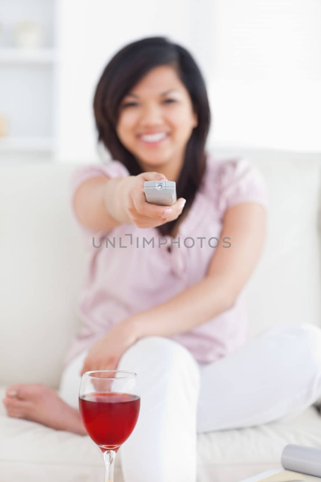 Woman sitting on a sofa while smiling and holding a remote in a living room