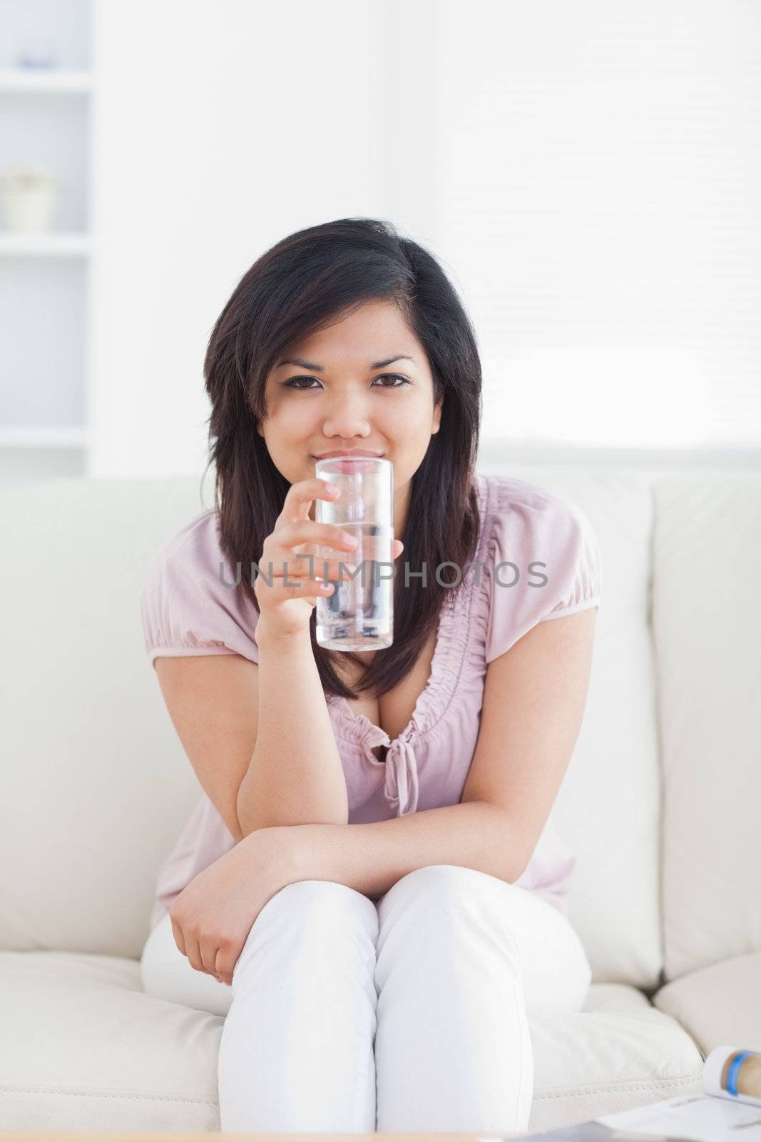 Woman drinking water while sitting in a couch in a living room