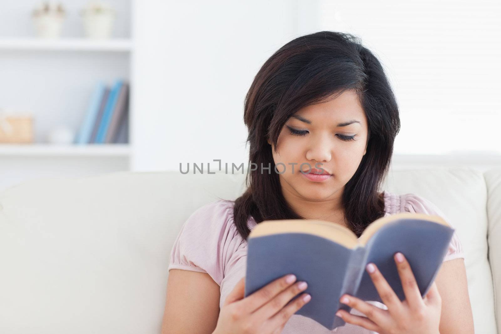 Woman sitting on a couch while reading a book in a living room