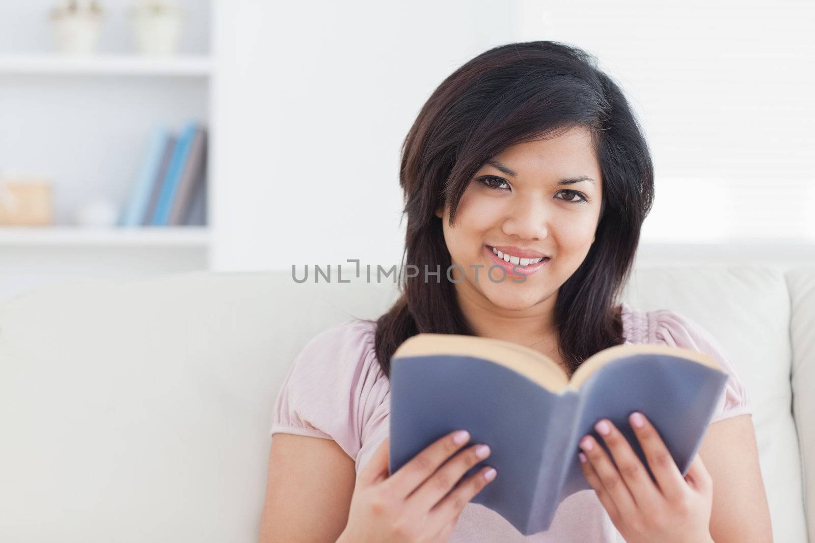 Woman sitting on a couch while holding a book in a living room