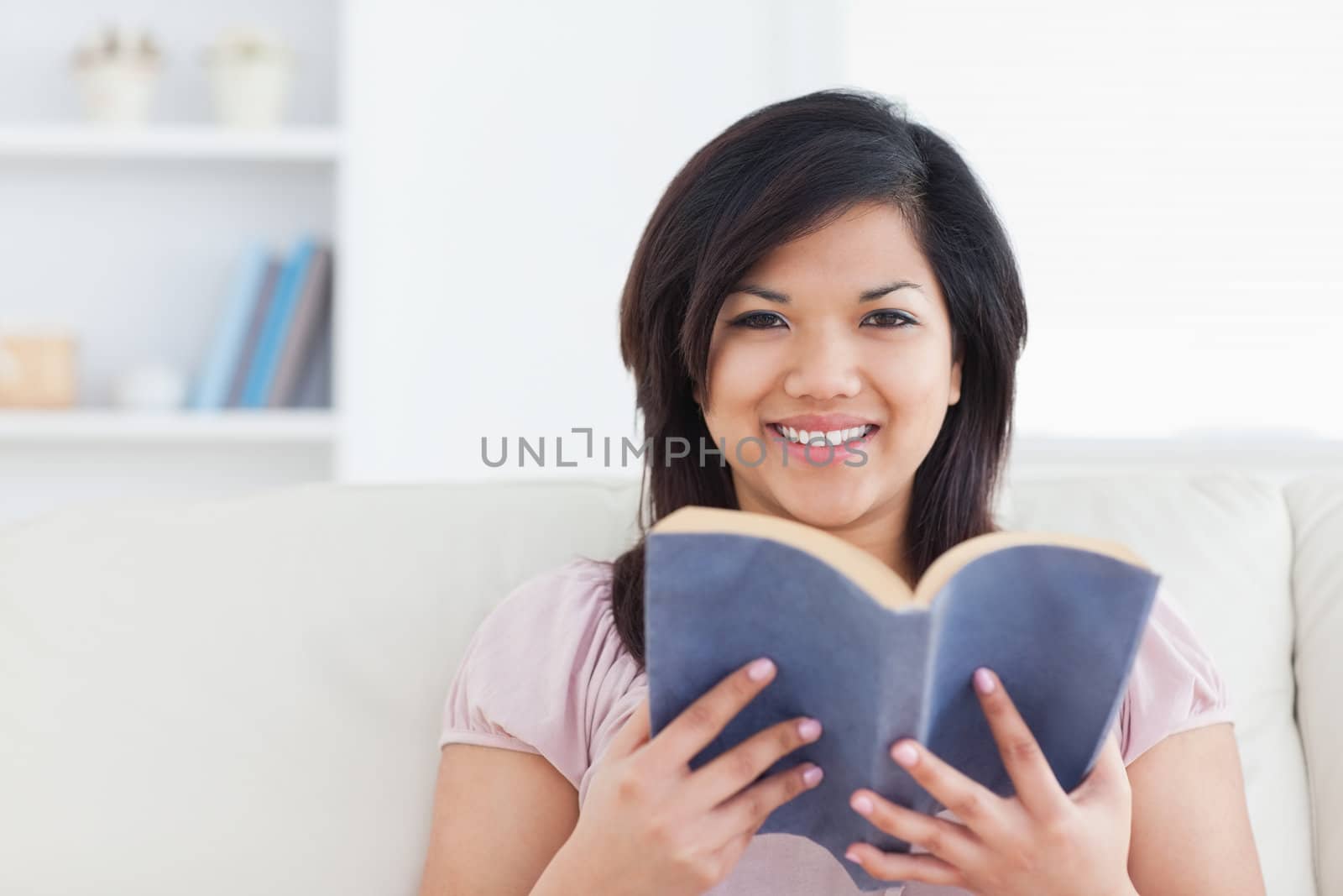 Woman smiling while holding a book in a living room