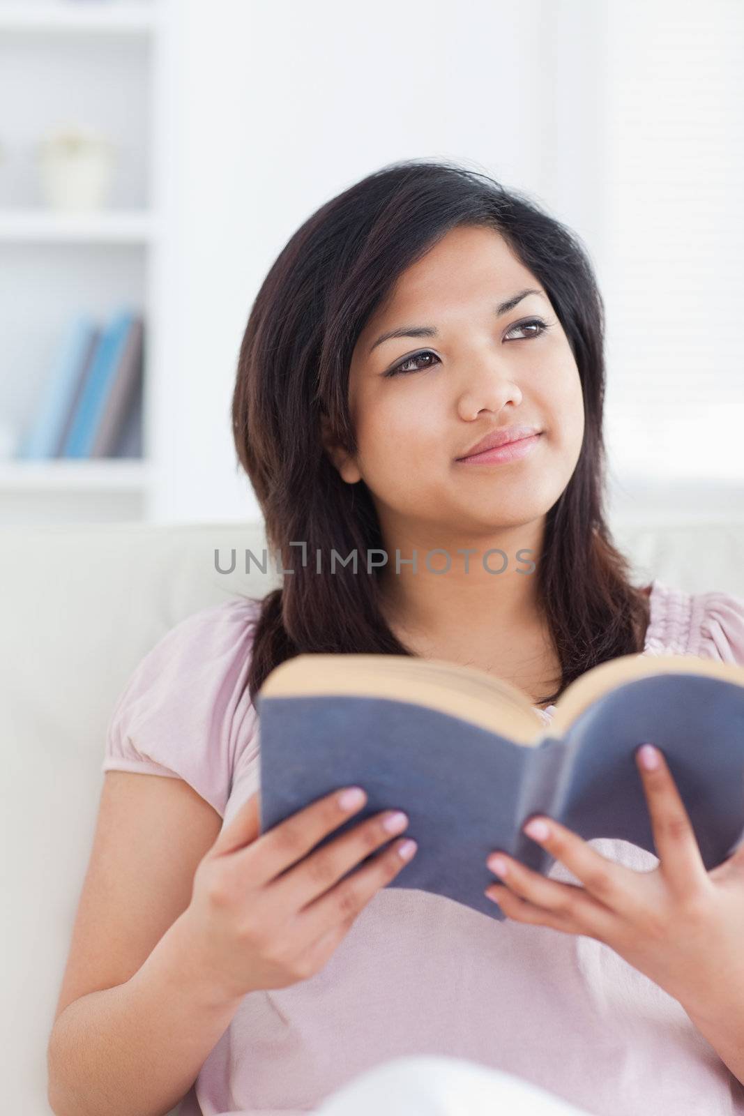 Woman sitting on a sofa while she holds a book in a living room