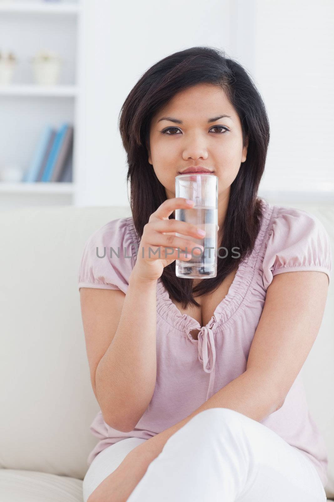 Woman sitting on a couch and holding a glass of water in a living room