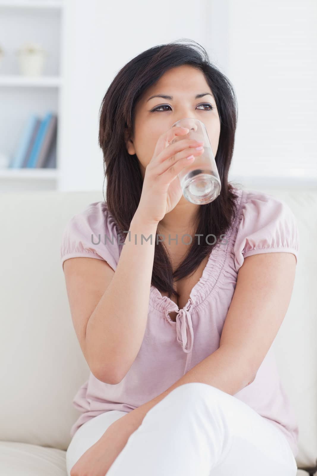Woman drinking water from a glass in a living room