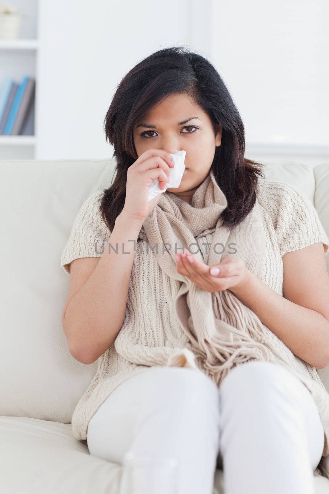 Woman blowing her nose in a living room