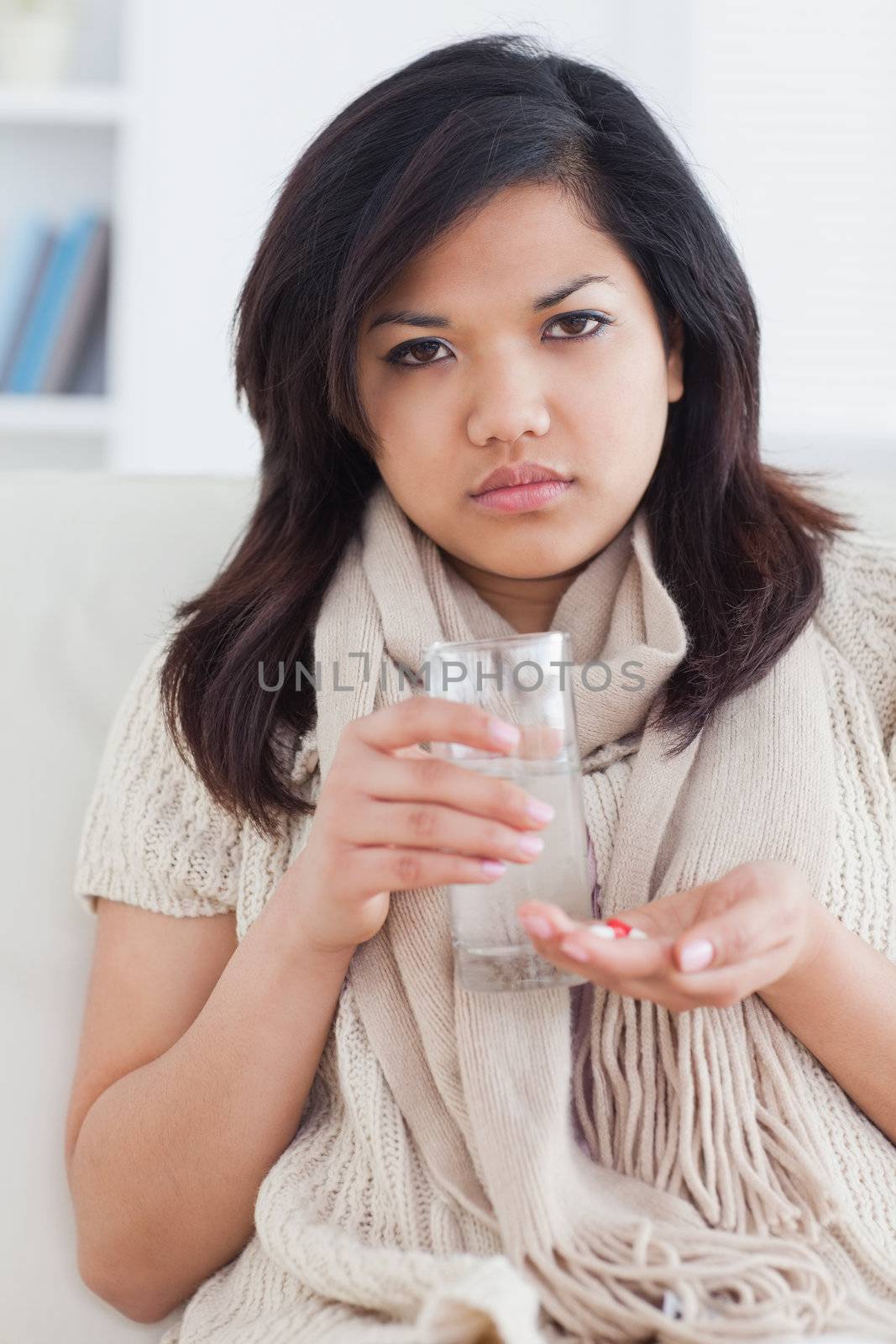 Sick woman taking pills in a living room