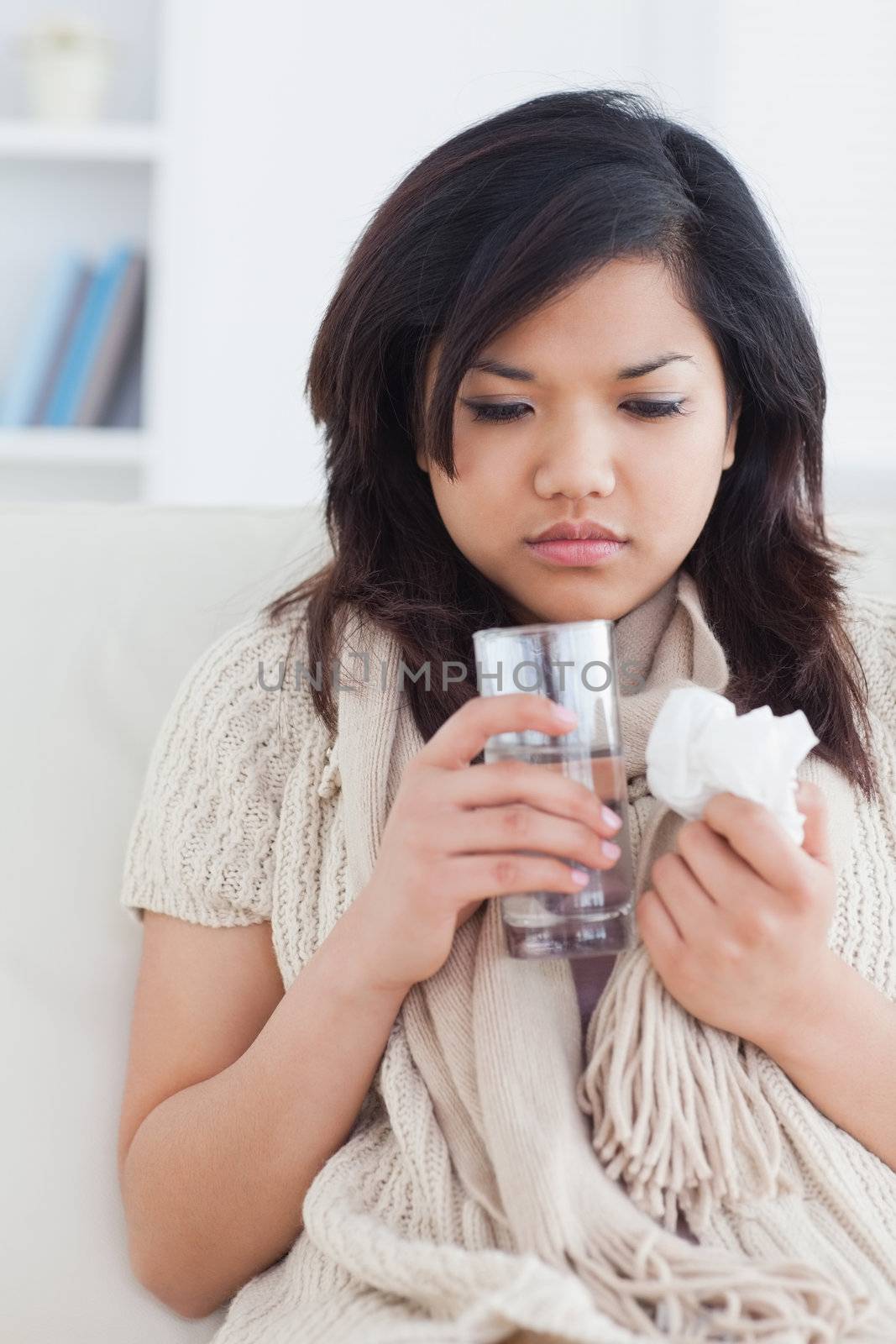Sick woman holding a glass of water in a living room