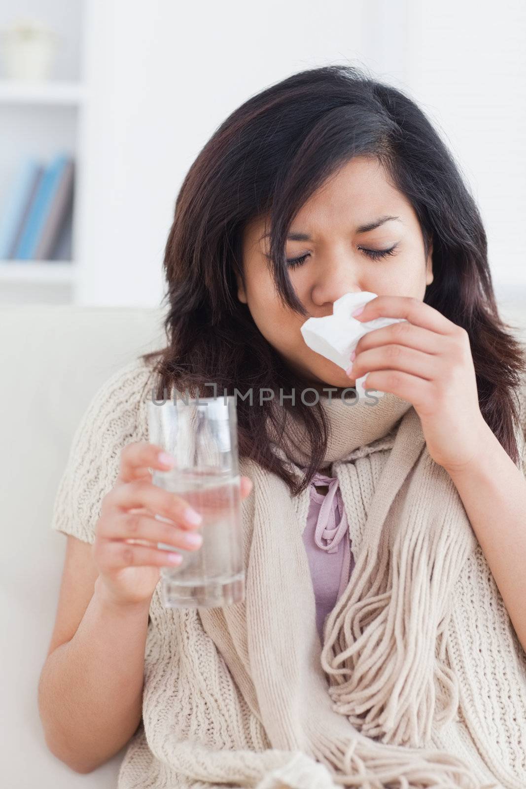 Sick woman blowing her nose in a living room