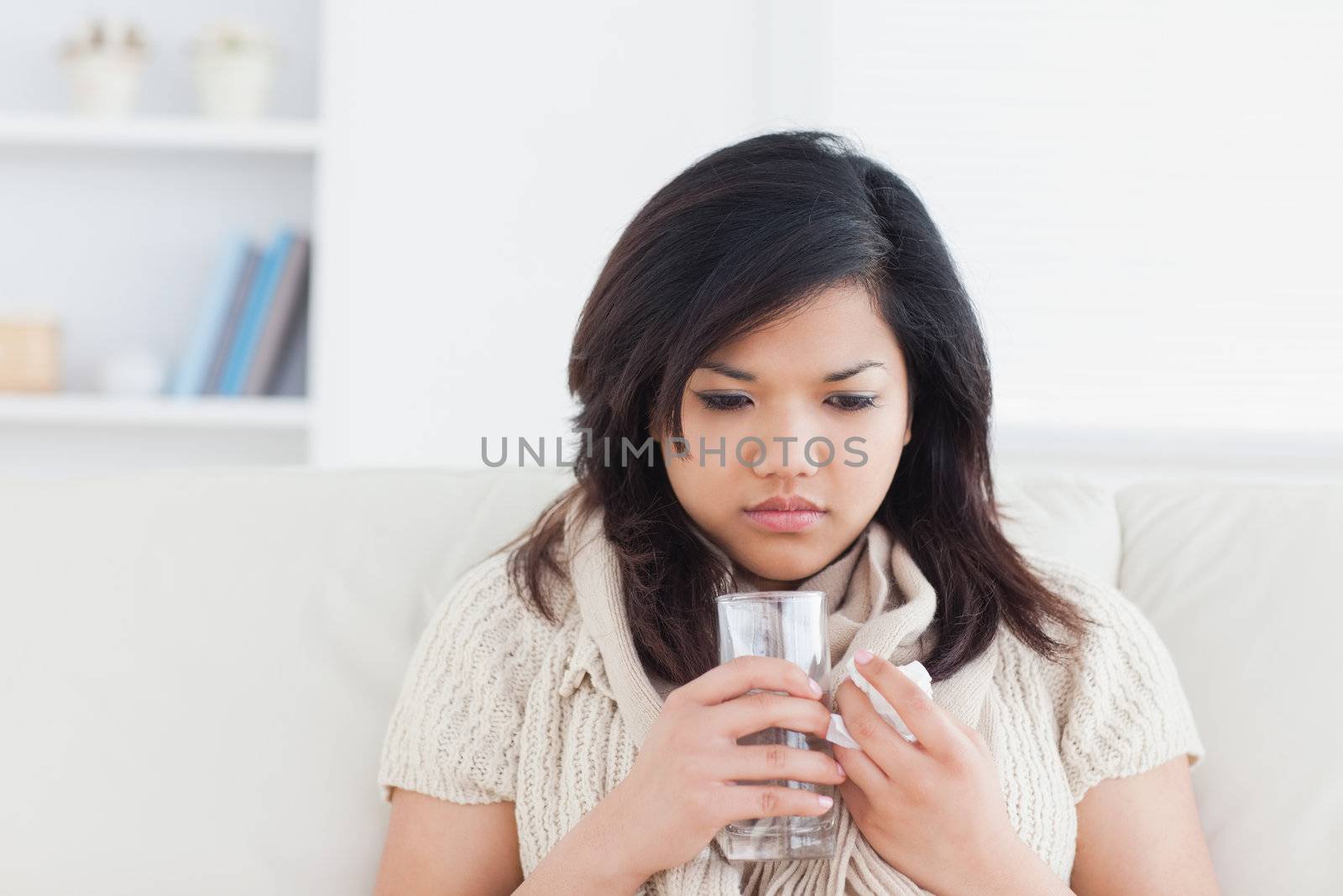 Woman holding a glass of water while being cold in a living room