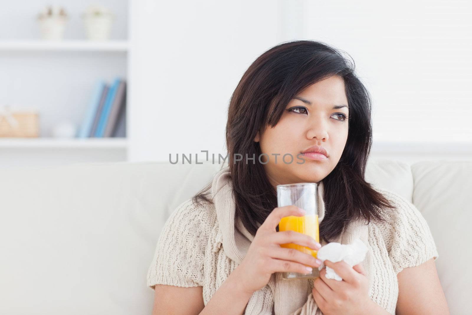 Sick woman holding a glass of orange juice in a living room