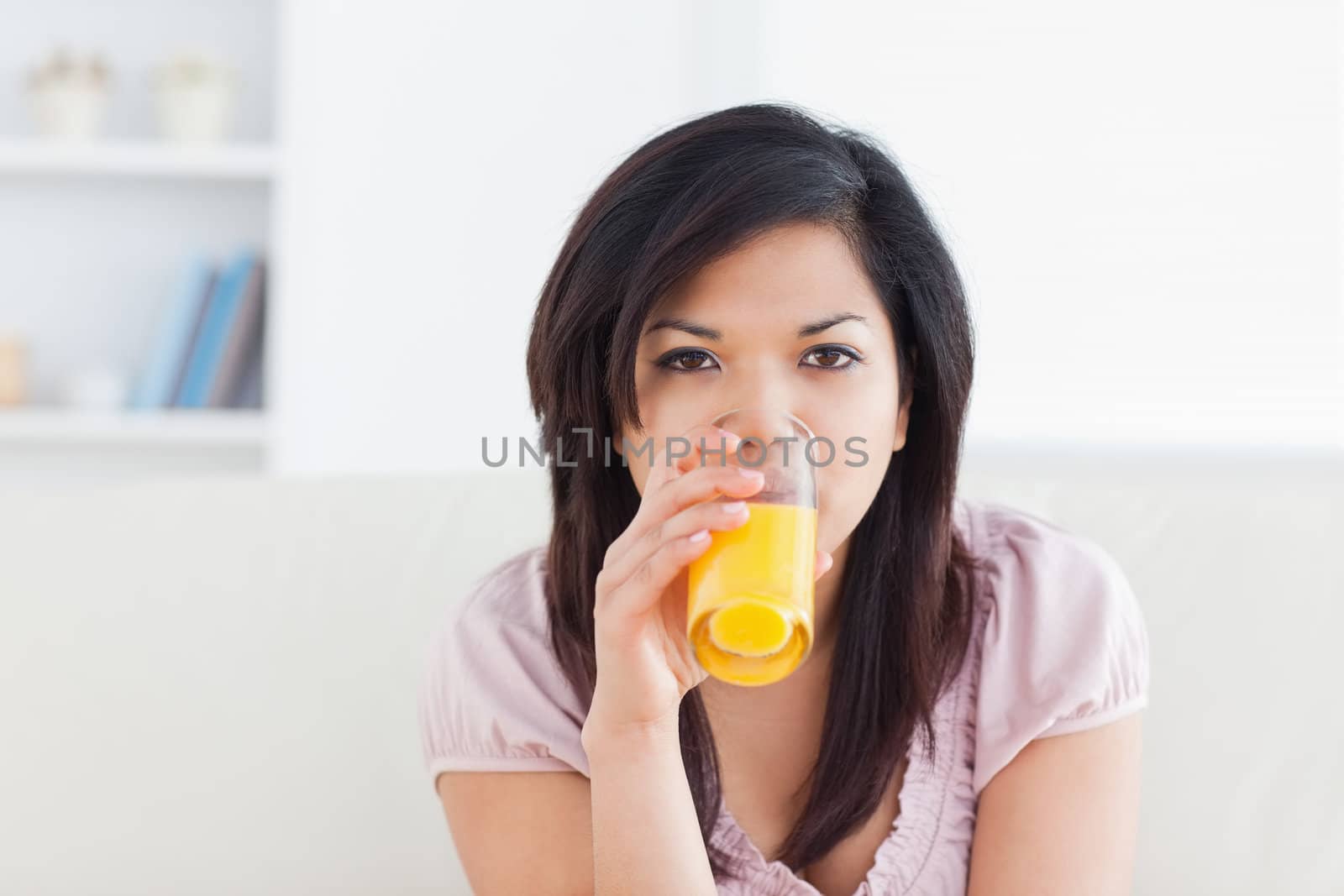 Woman drinking a glass of orange juice in a living room