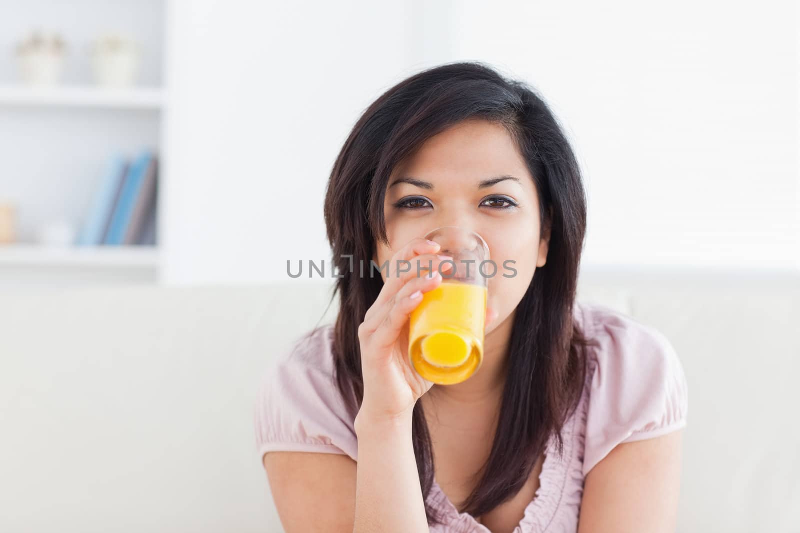 Woman smiling while drinking a glass of orange juice in a living room