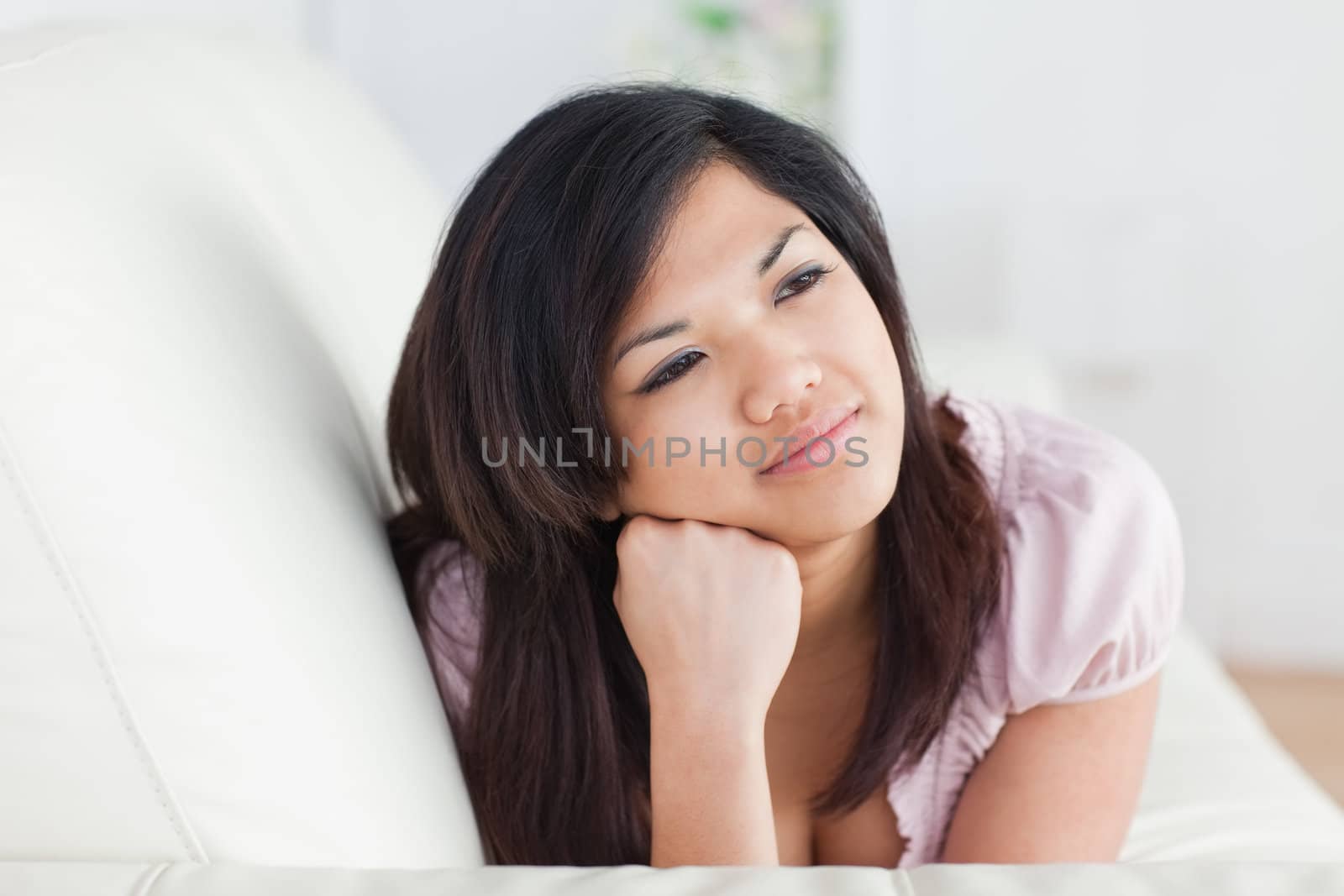 Woman resting on a couch while holding her head with her hand in a living room