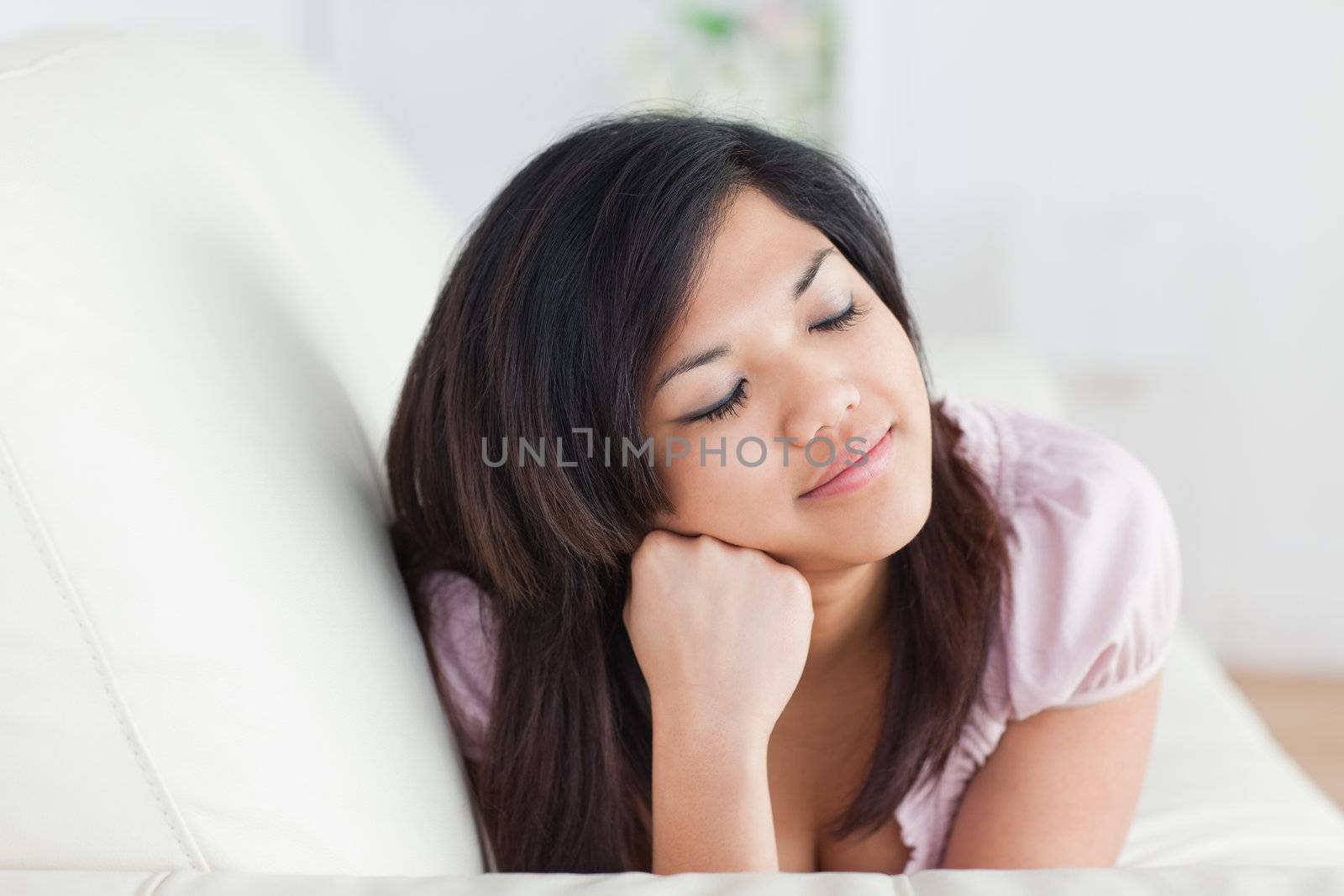 Woman closing her eyes while resting on a couch in a living room