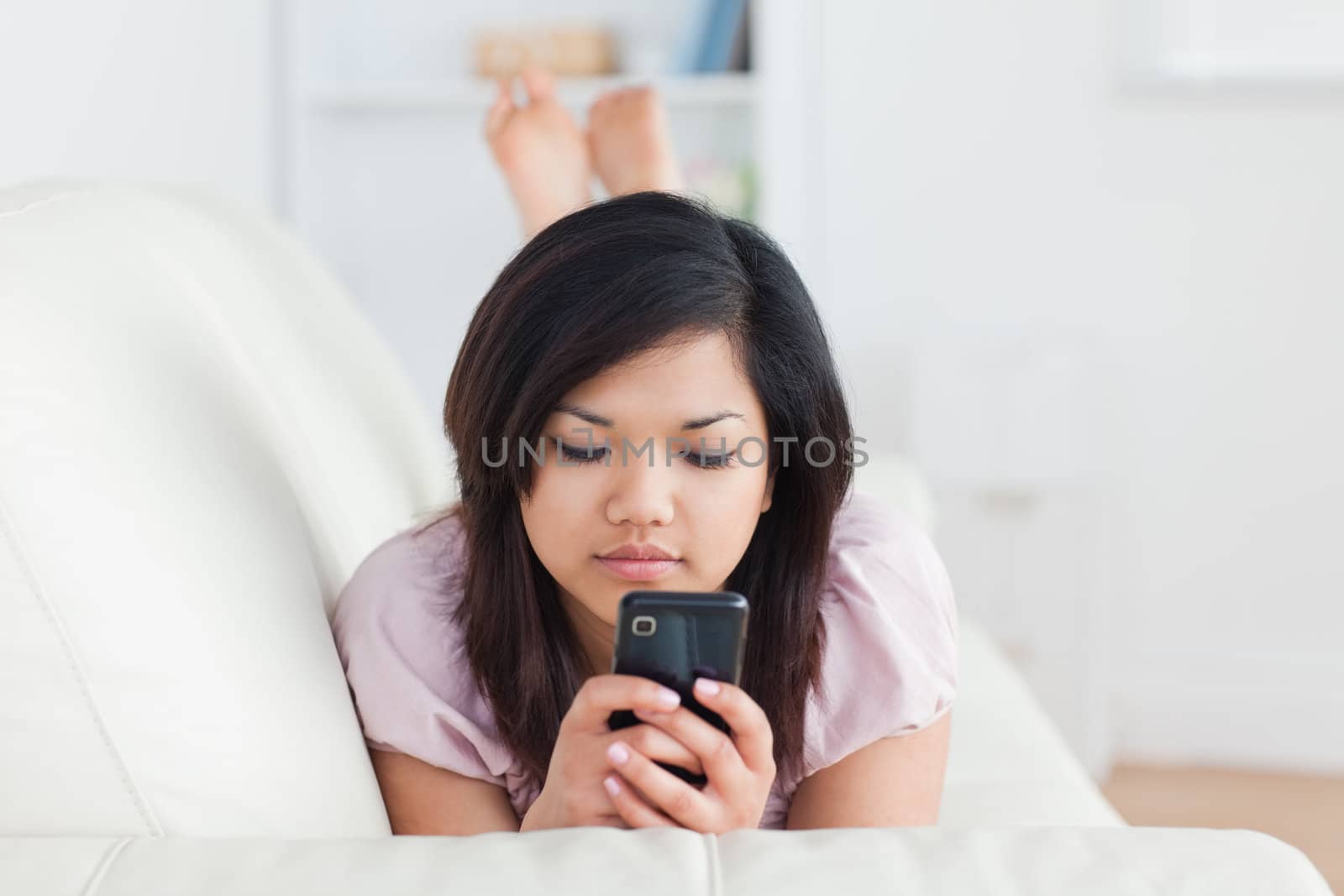 Woman lying on a sofa while holding a telephone in a living room