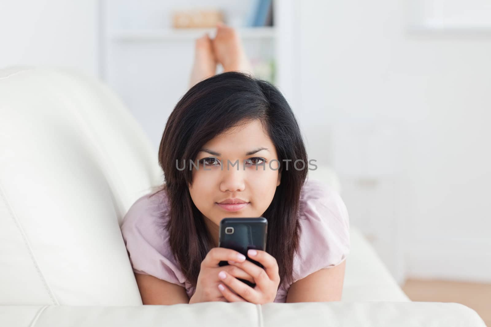Woman resting on a couch while holding a telephone in a living room