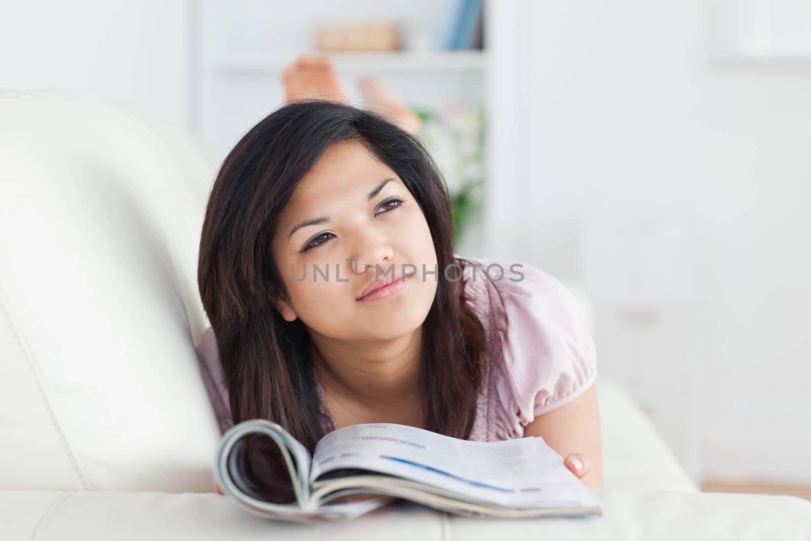 Woman lays on a sofa while reading a magazine in a living room