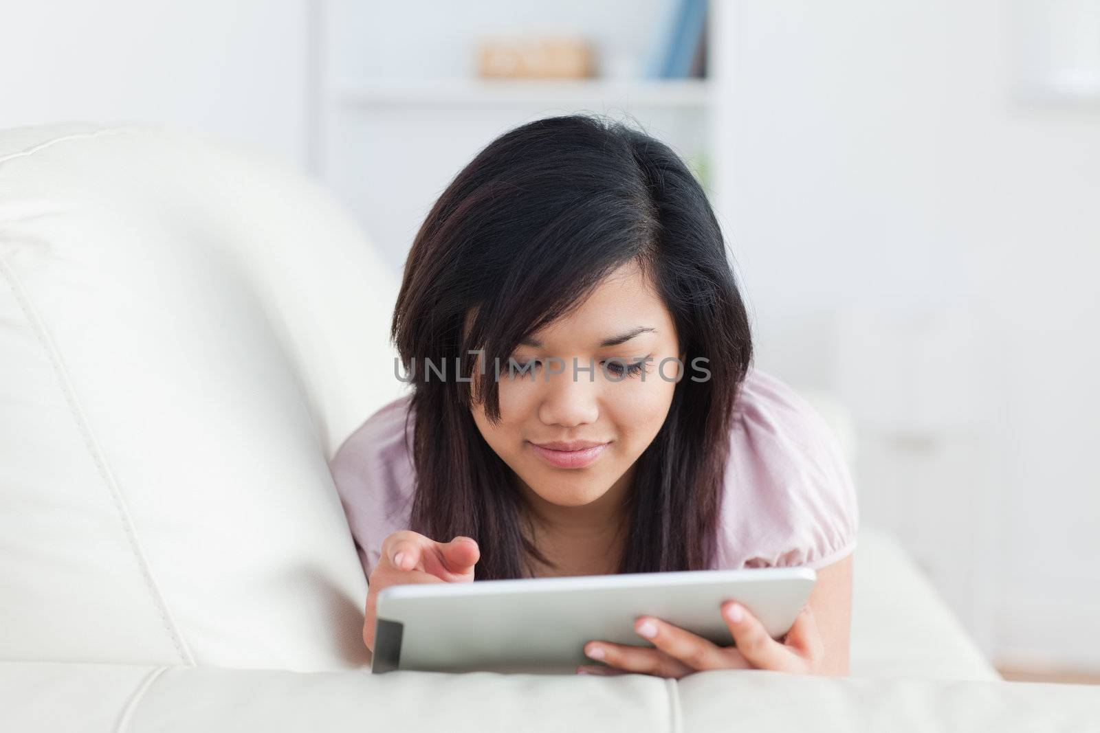 Woman lying on a couch while holding a tablet in a living room
