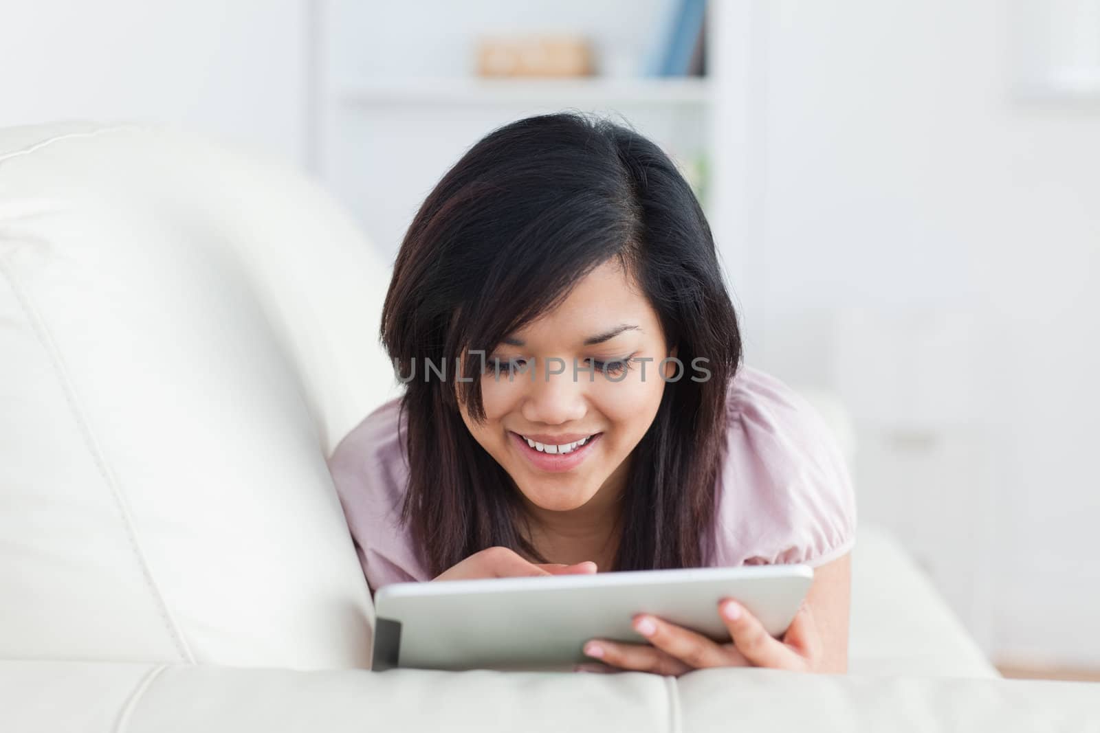 Woman resting on a sofa while touching a tablet in a living room