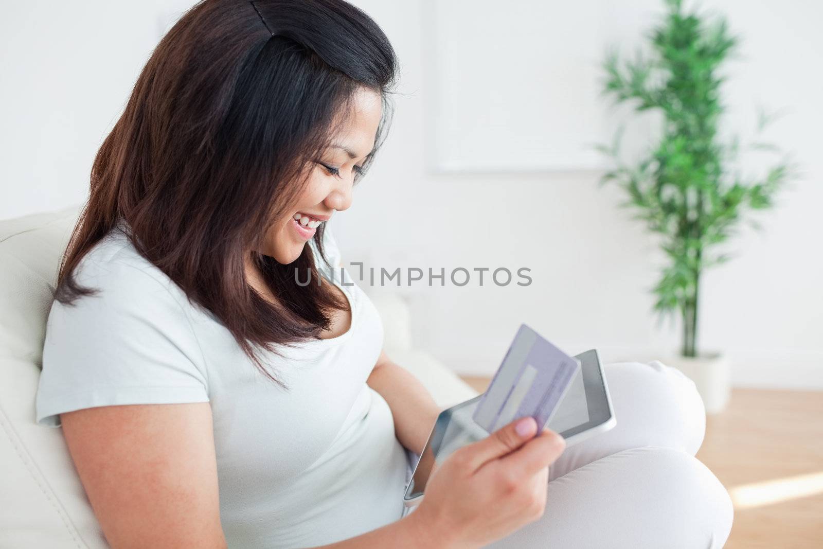 Woman on a couch while holding a tactile tablet and a card in a living room