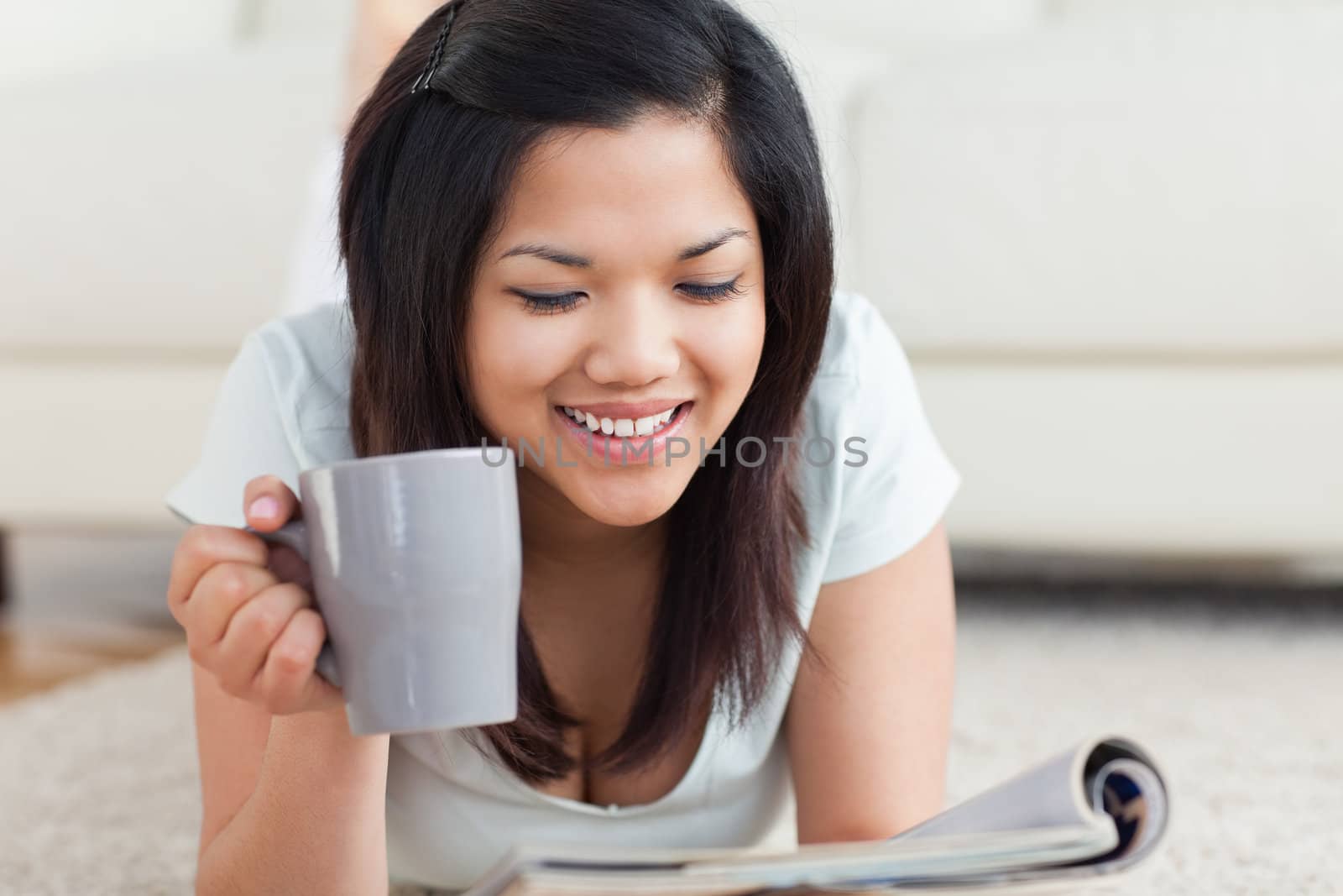Smiling woman holding a cup and a magazine in a living room
