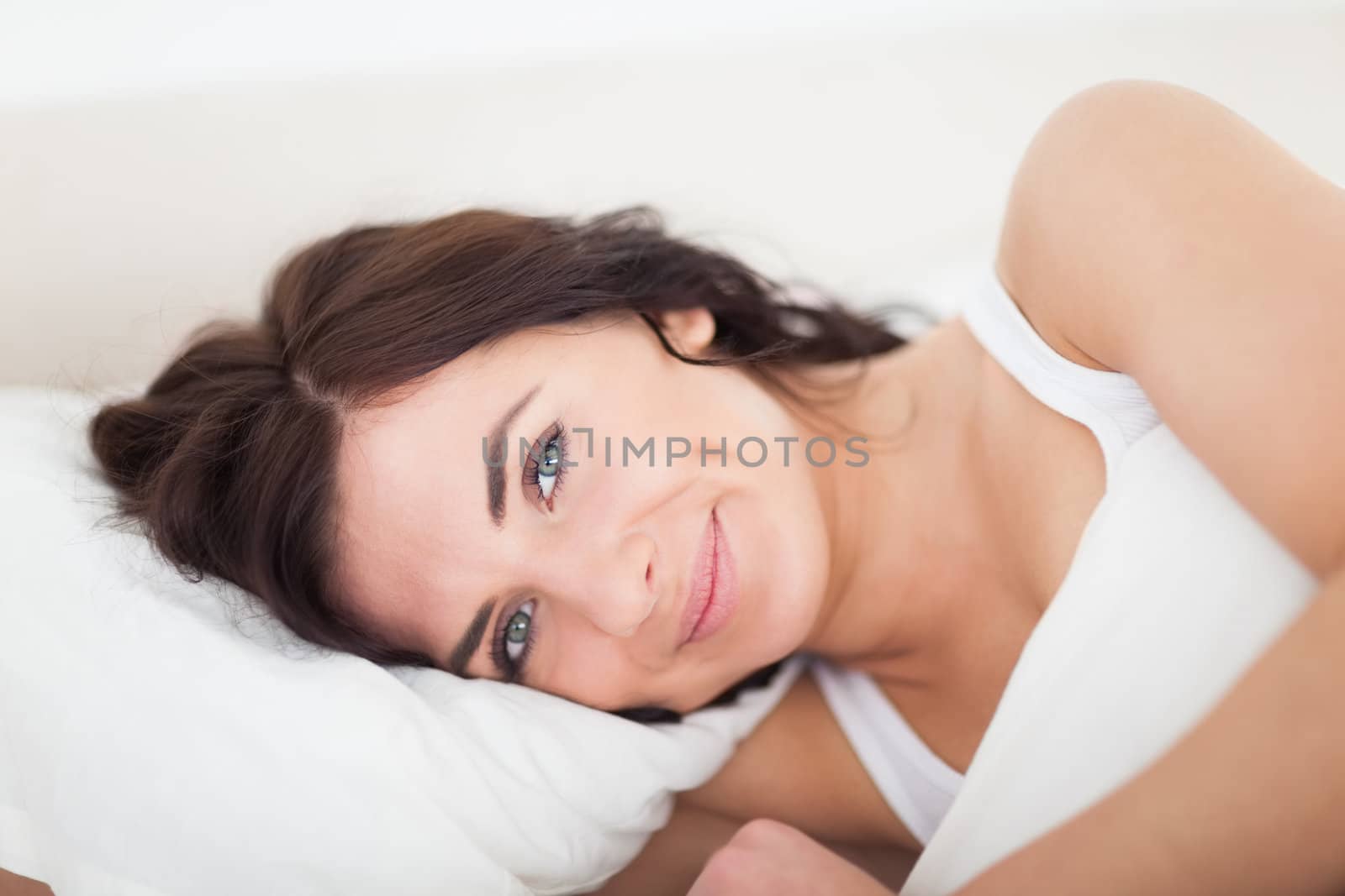 Smiling brunette woman waking up in her bedroom