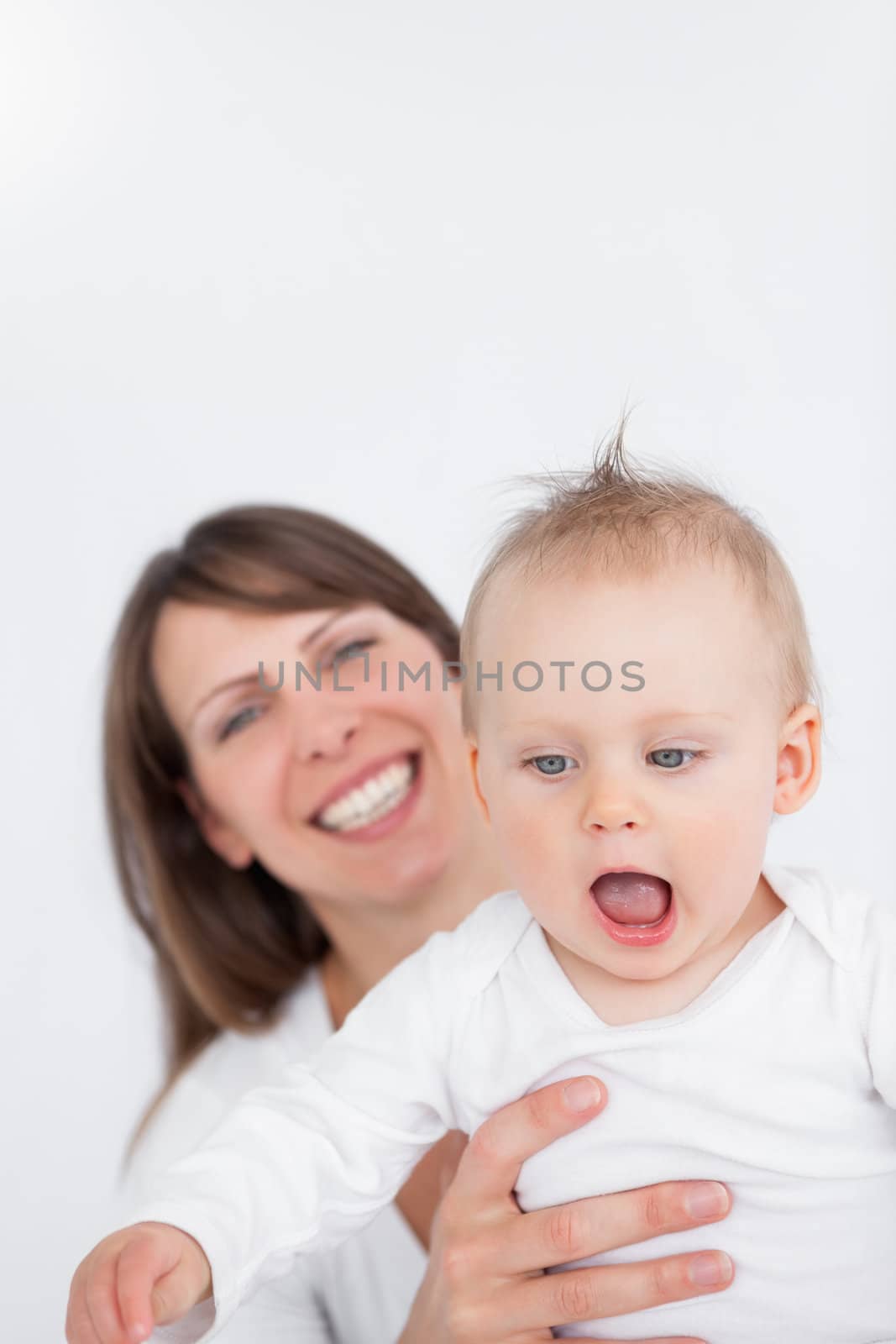 Happy woman playing with her baby against a grey background