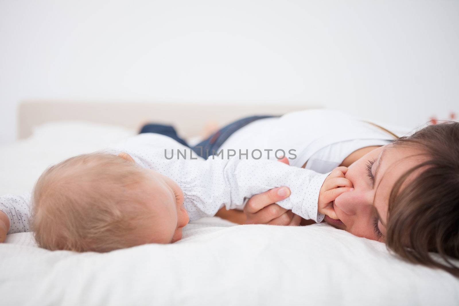 Cute baby placing her hand on the mouth of her mother by Wavebreakmedia