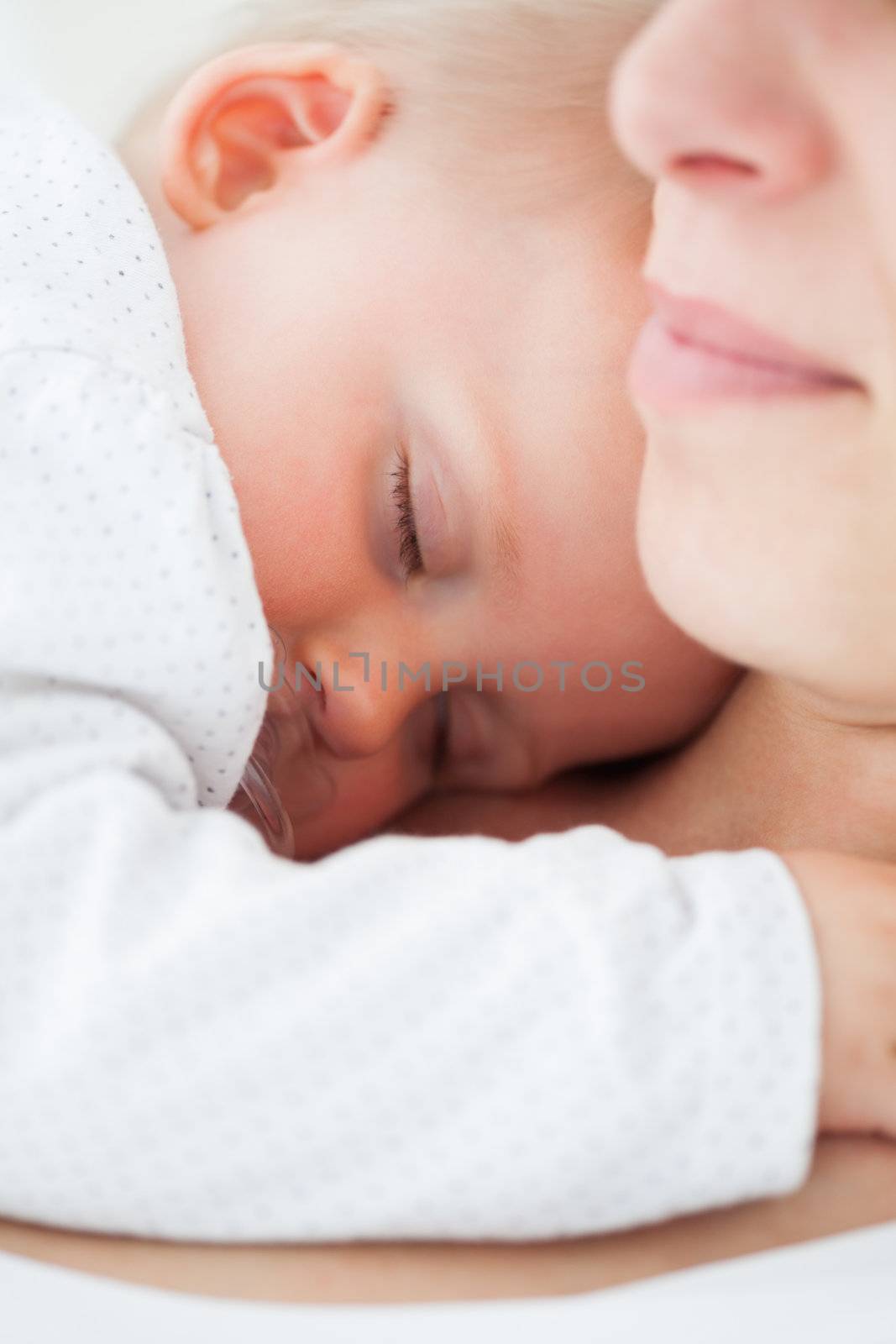 Baby napping on the chest of her mother by Wavebreakmedia