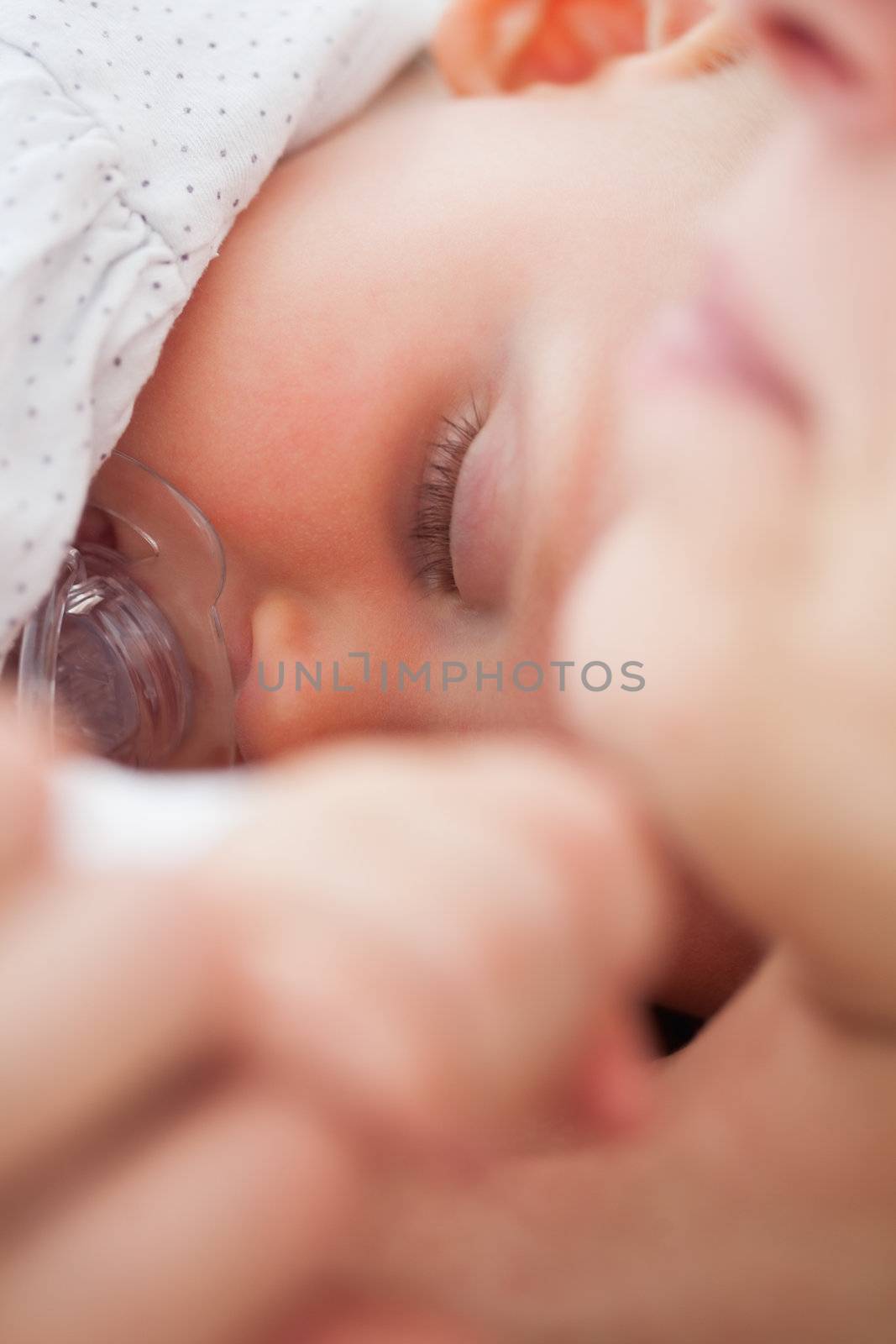Baby sleeping while sucking a pacifier by Wavebreakmedia