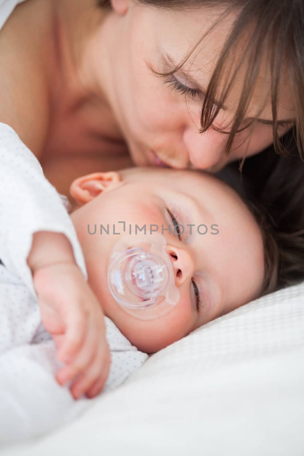 Brunette woman kissing the head of her baby indoors