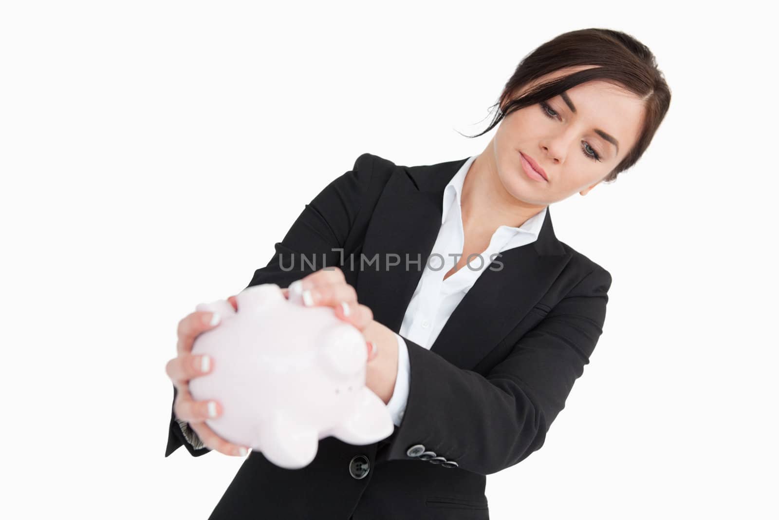 Young woman in suit emptying a piggy bank against white background