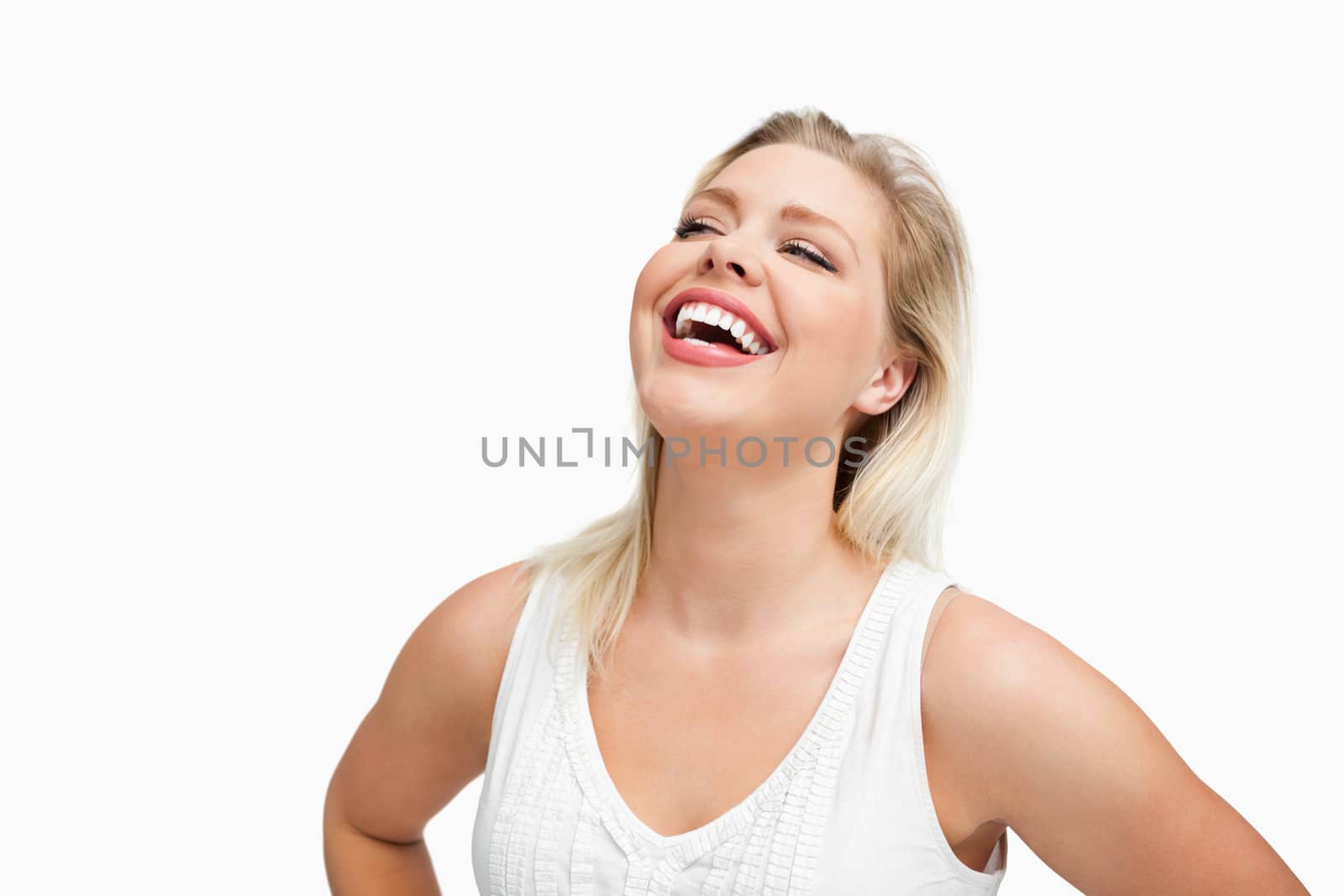 Happy woman laughing with her hands on her hips against a white background