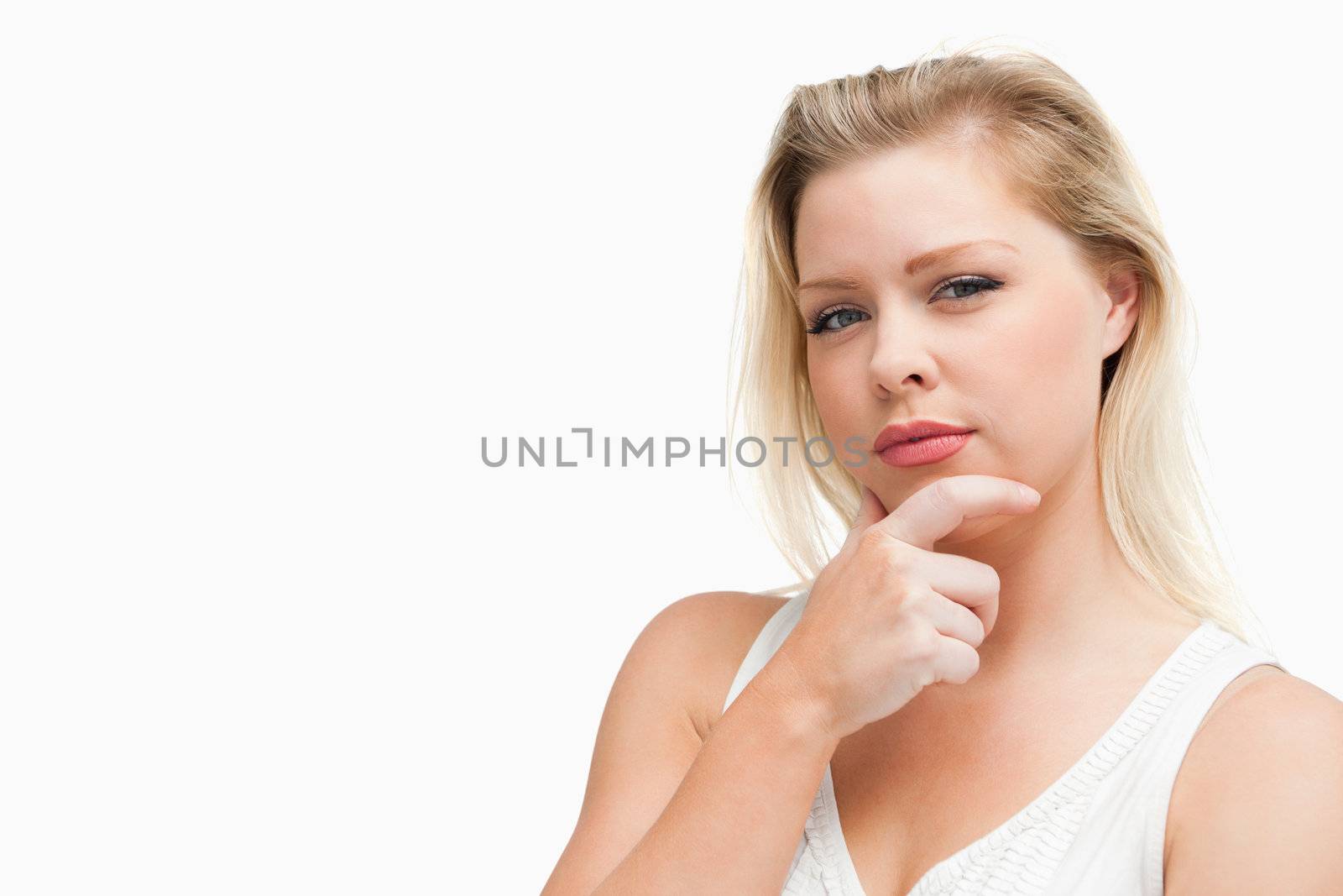 Serious blonde woman placing her hand on her chin against a white background