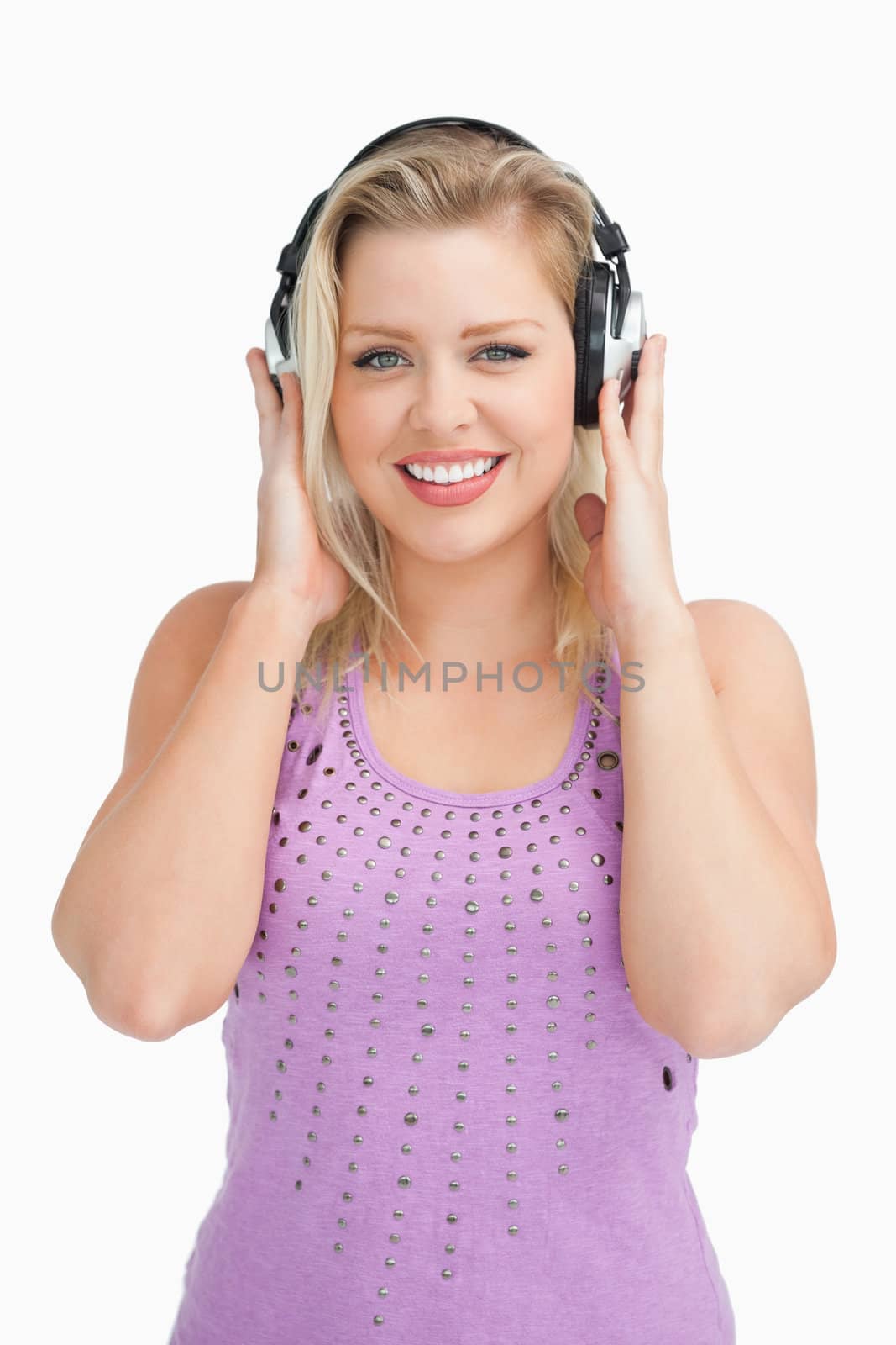 Happy blonde woman placing her hands on her headphones against a white background