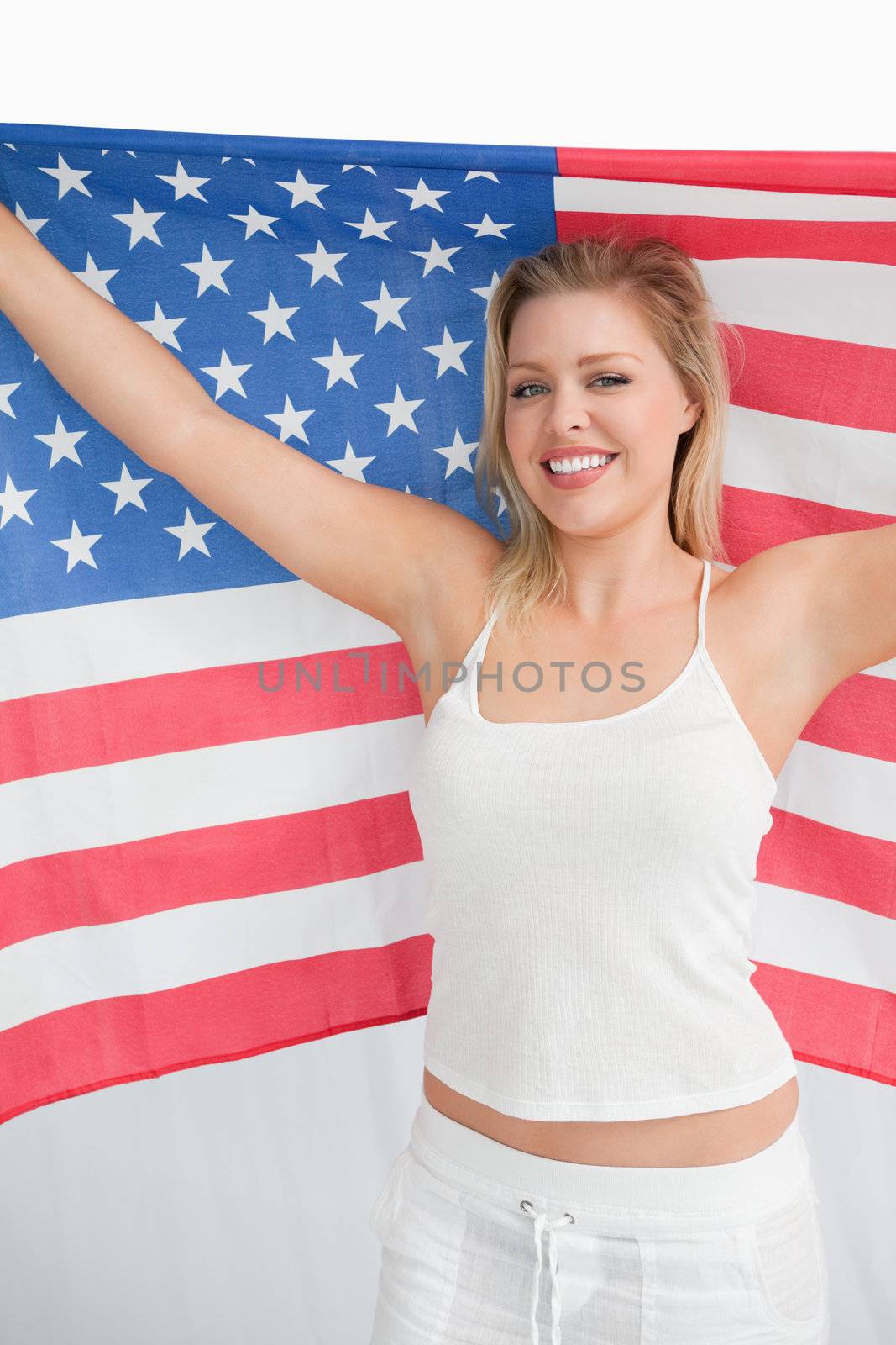 Happy blonde woman holding the Old Glory flag against a white background