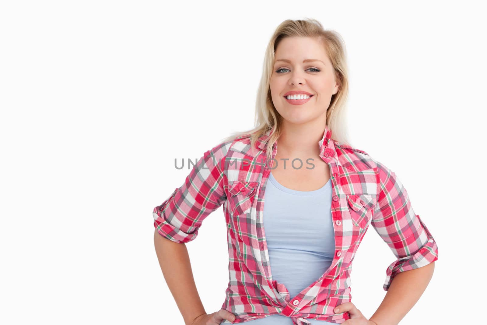 Smiling blonde woman putting her hands on her hips against a white background