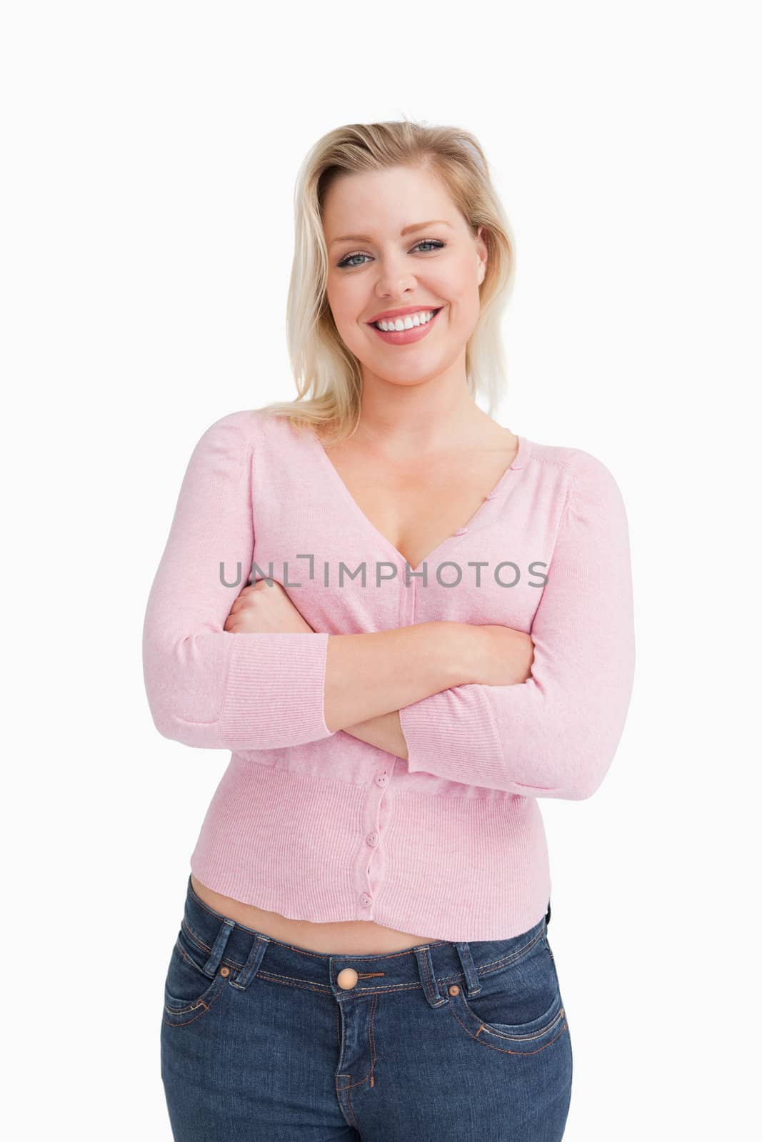 Smiling blonde crossing her arms while standing against a white background