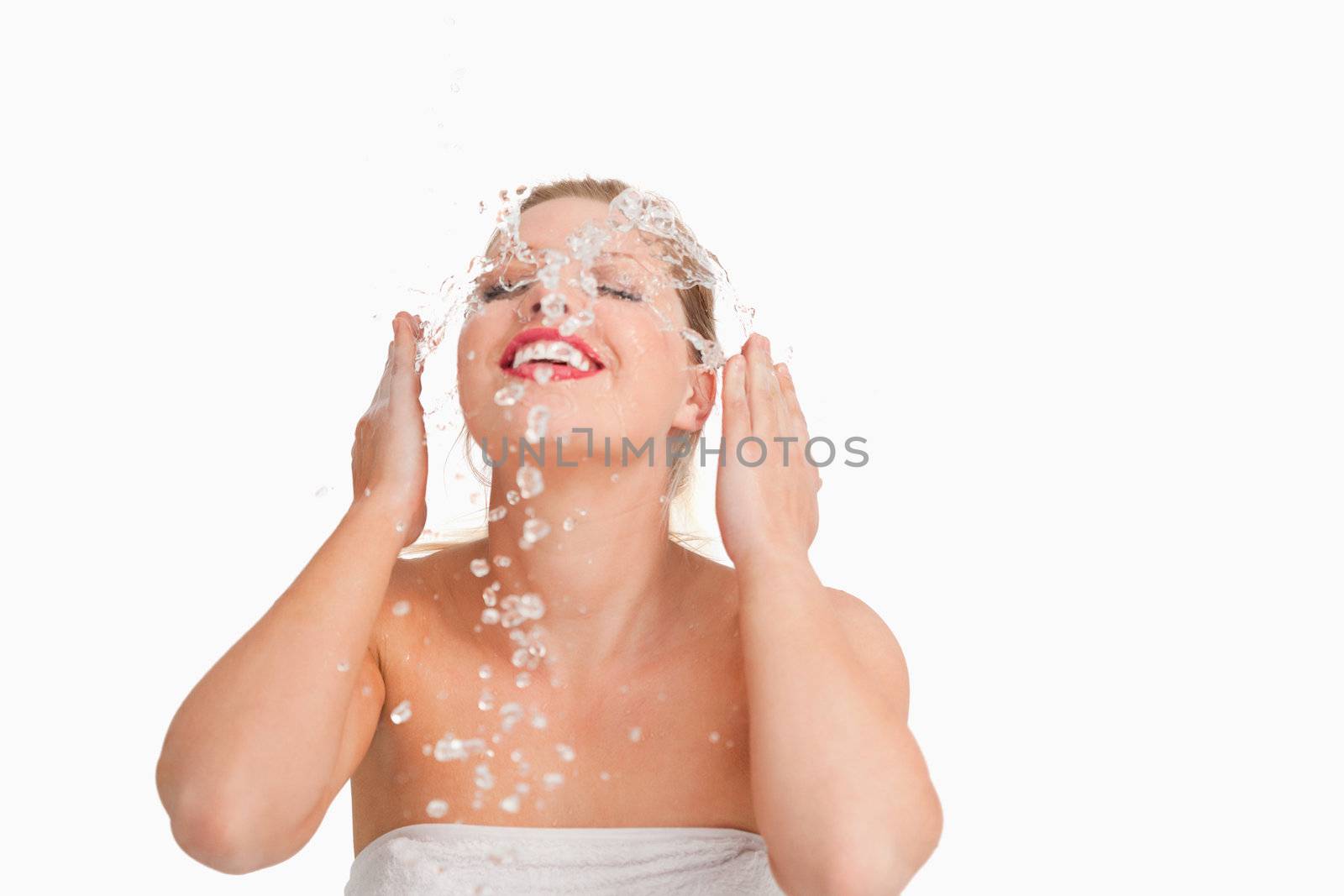 Blonde woman splashing her face against a white background
