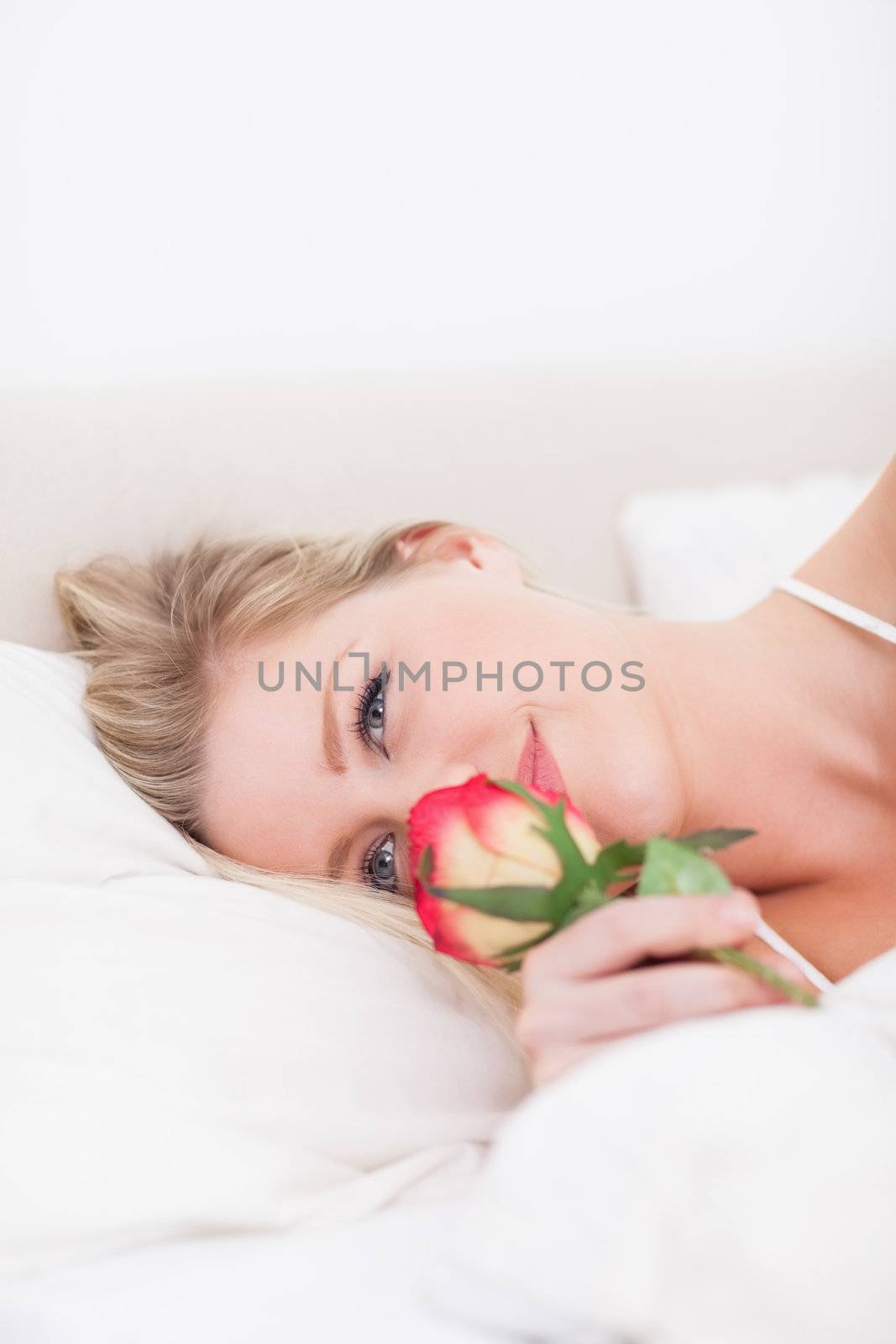 Blue eyed woman smelling a rose by Wavebreakmedia