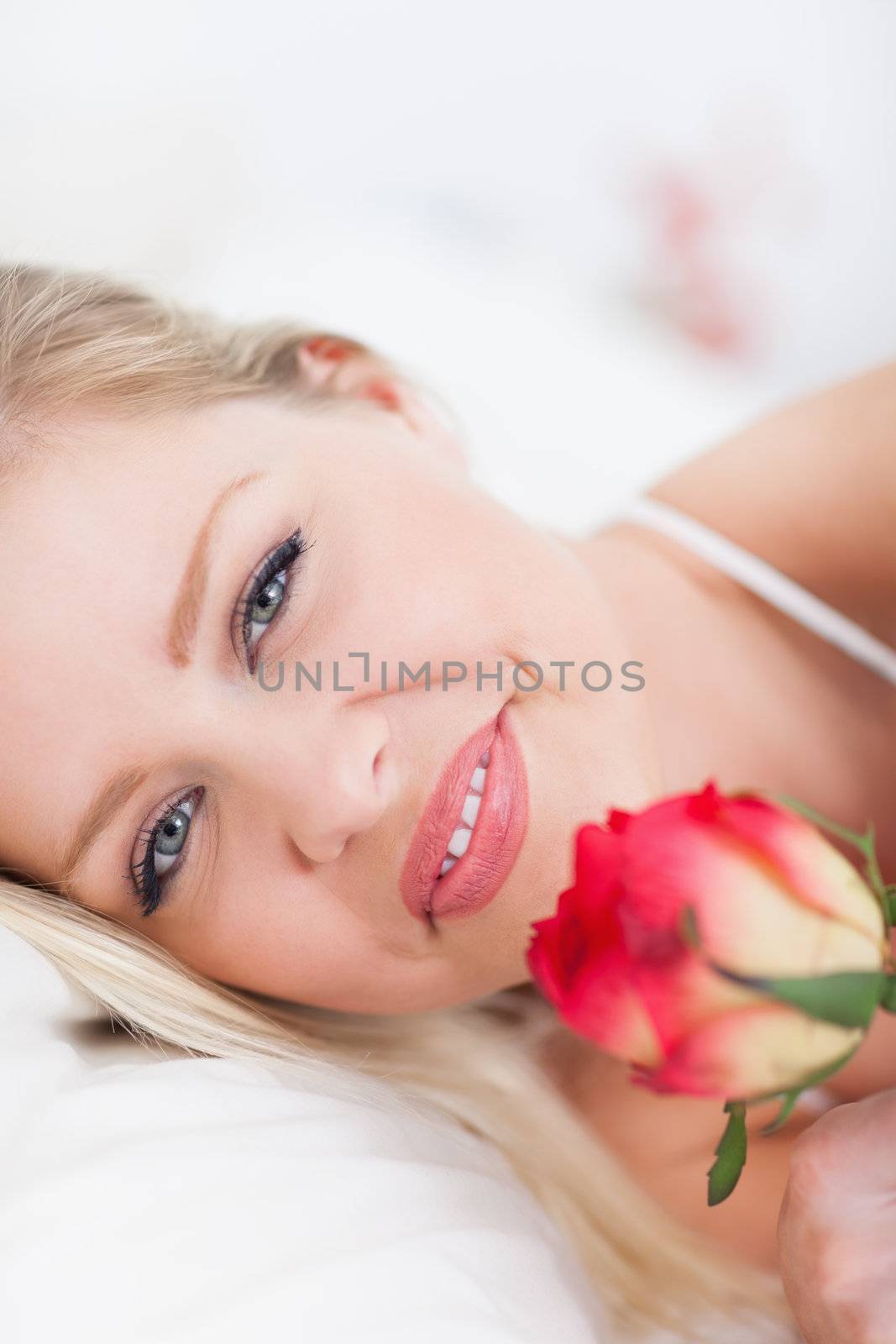 Blue eyed woman with a rose in a bed