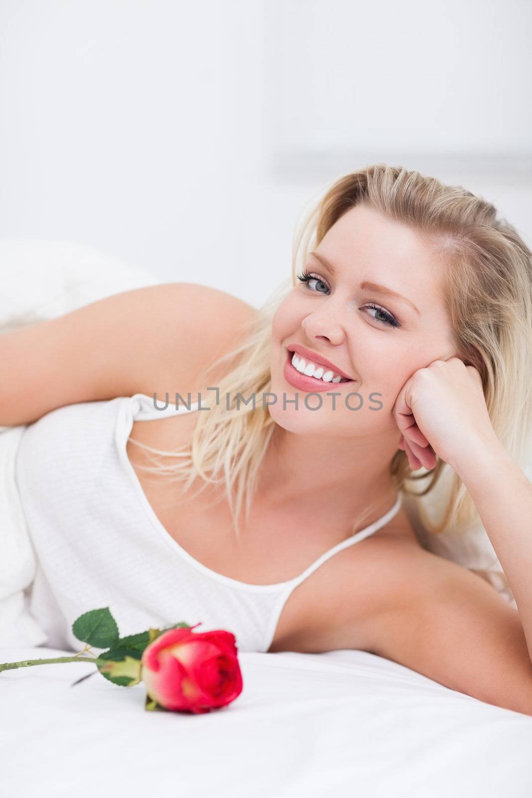 Woman with a rose smiling on her bed