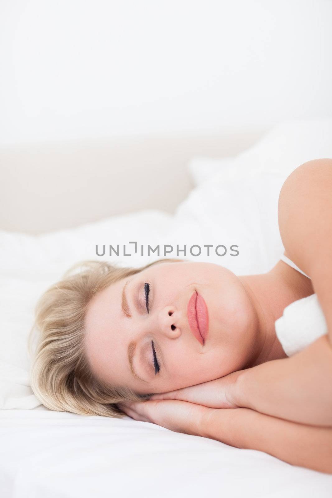 Young woman sleeping with a smile in her bed